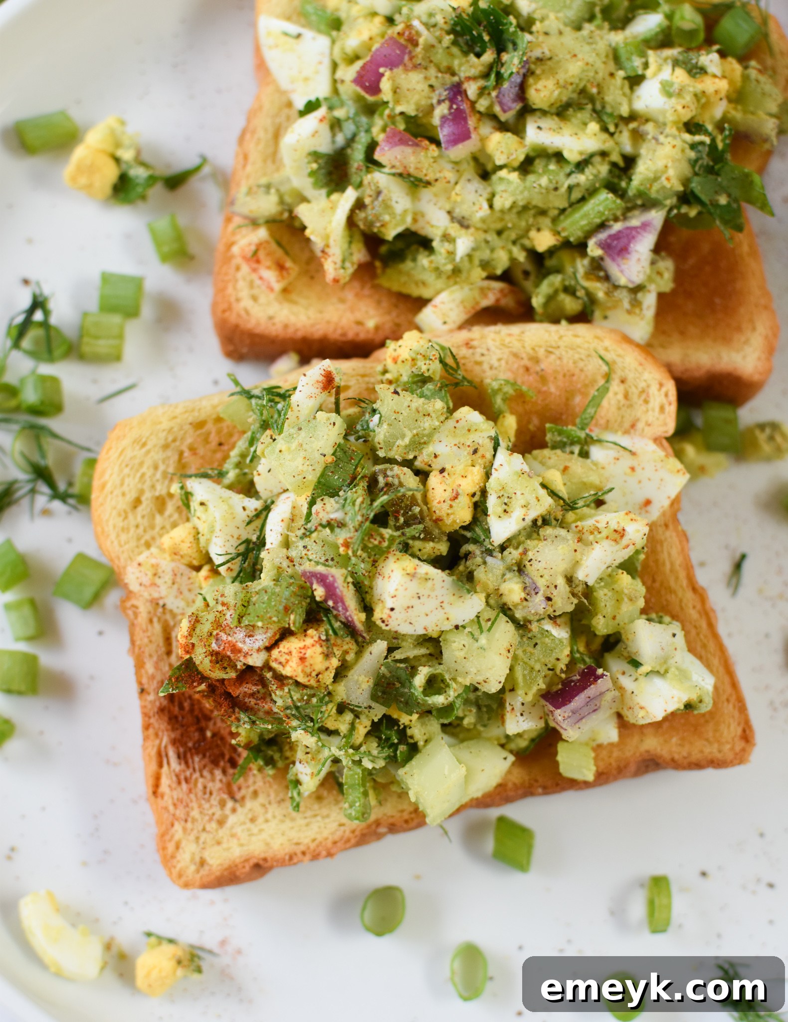 Creamy Avocado Egg Salad with fresh dill and parsley, presented artfully on toasted brioche or a vibrant bed of lettuce.