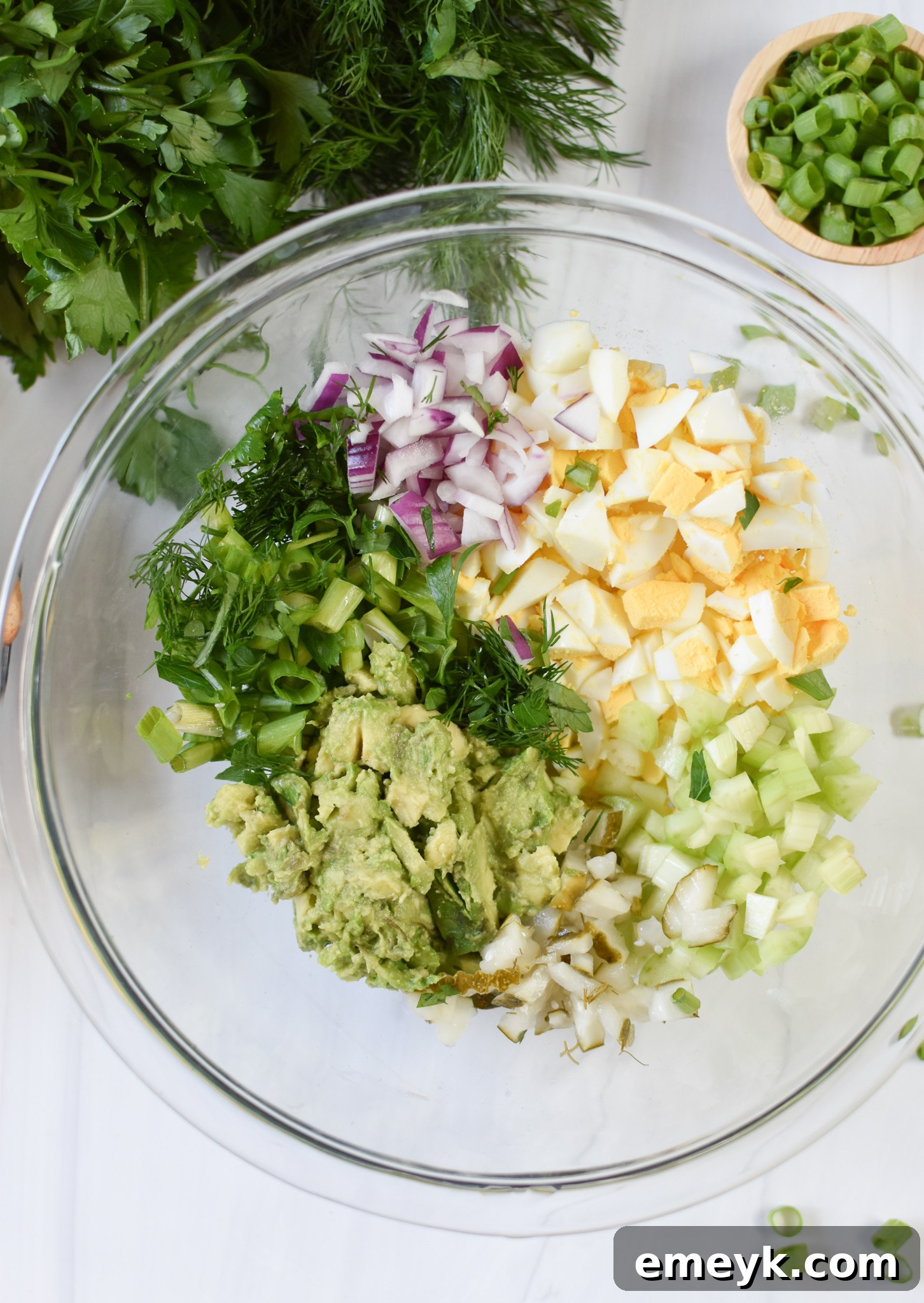 All the vibrant, fresh ingredients for Avocado Egg Salad meticulously prepared and gathered in a mixing bowl, awaiting the addition of the chopped eggs.