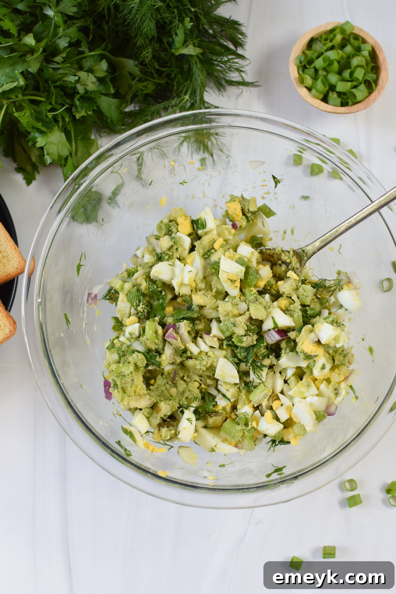 Freshly mixed Avocado Egg Salad, featuring creamy avocado and perfectly chopped ingredients, presented invitingly in a glass bowl.