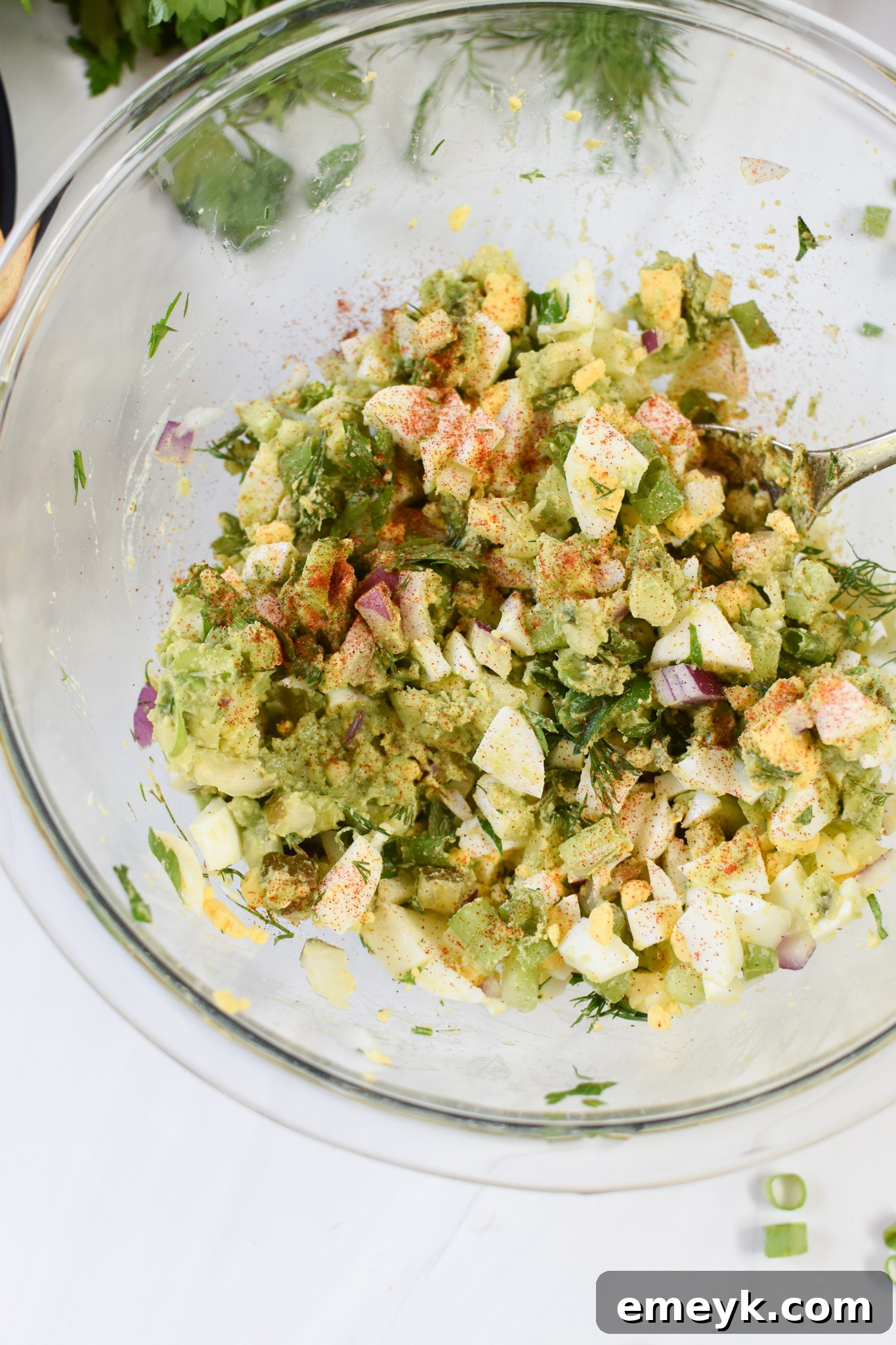 Close-up view of freshly mixed Avocado Egg Salad in a mixing bowl, showcasing the creamy avocado beautifully blended with perfectly chopped eggs and vibrant vegetables.