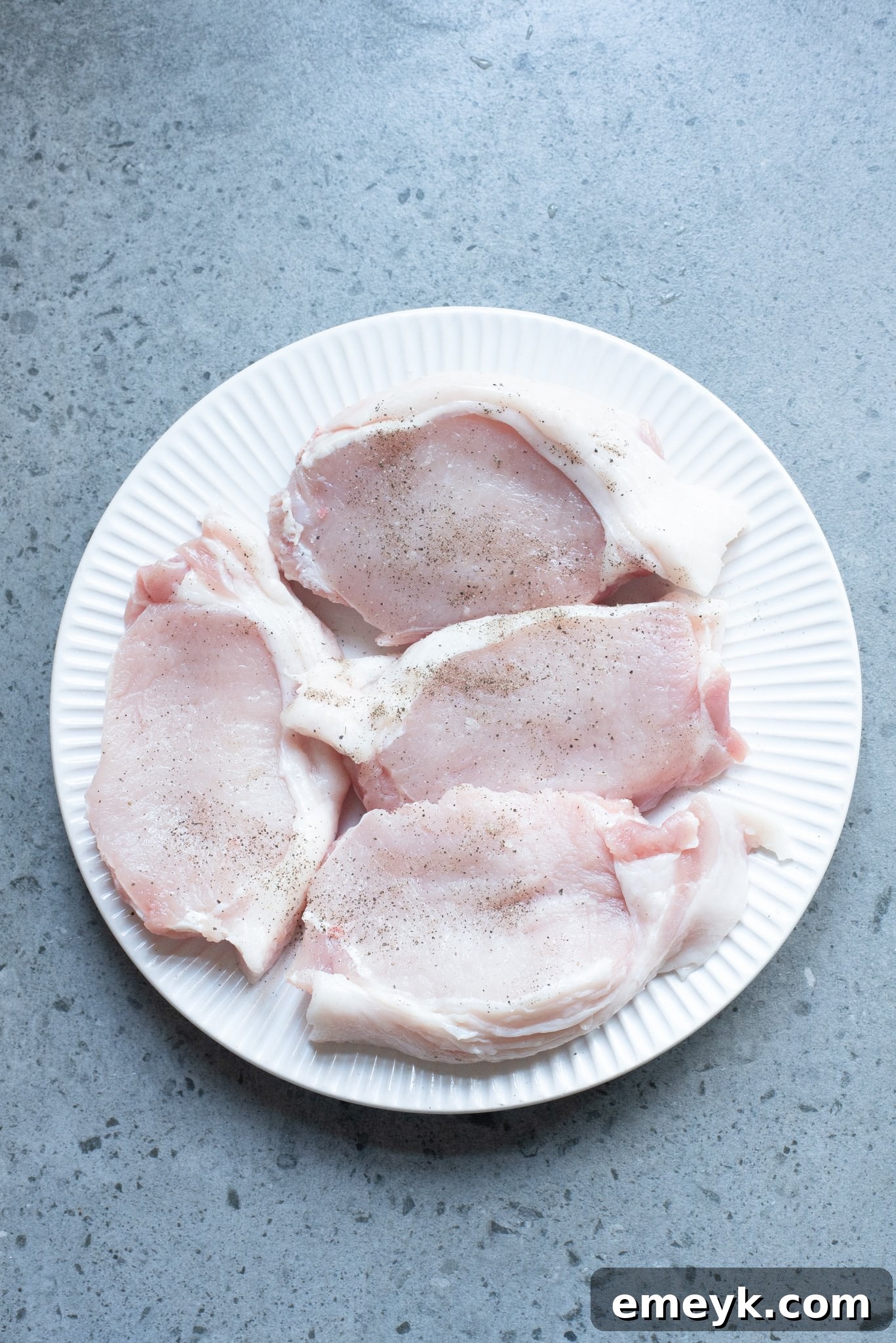 Boneless pork chops seasoned with garlic powder, salt, and pepper, searing in a hot skillet until golden brown.