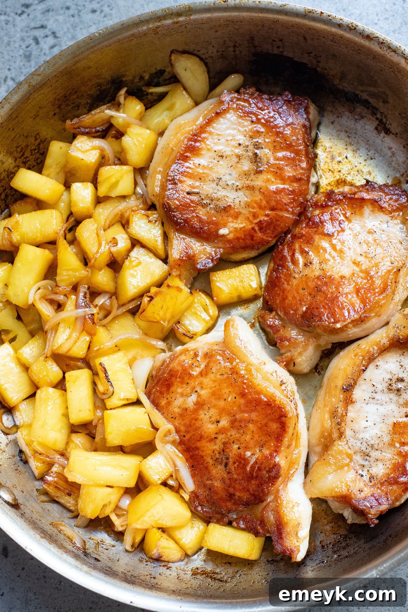 The finished Easy Pineapple Pork Chops dish, served hot in the skillet, generously coated in the glossy sweet and sour pineapple sauce, garnished with fresh herbs.