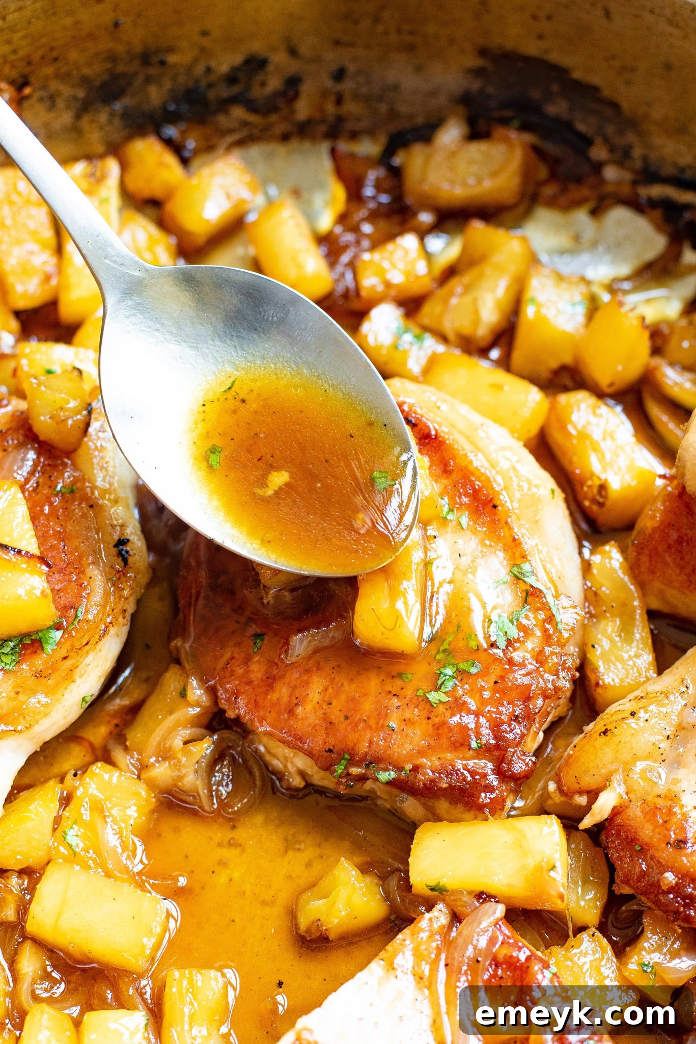 A close-up of tender, juicy pineapple pork chops generously coated in the glossy sweet and sour sauce, highlighting the texture and richness of the dish.