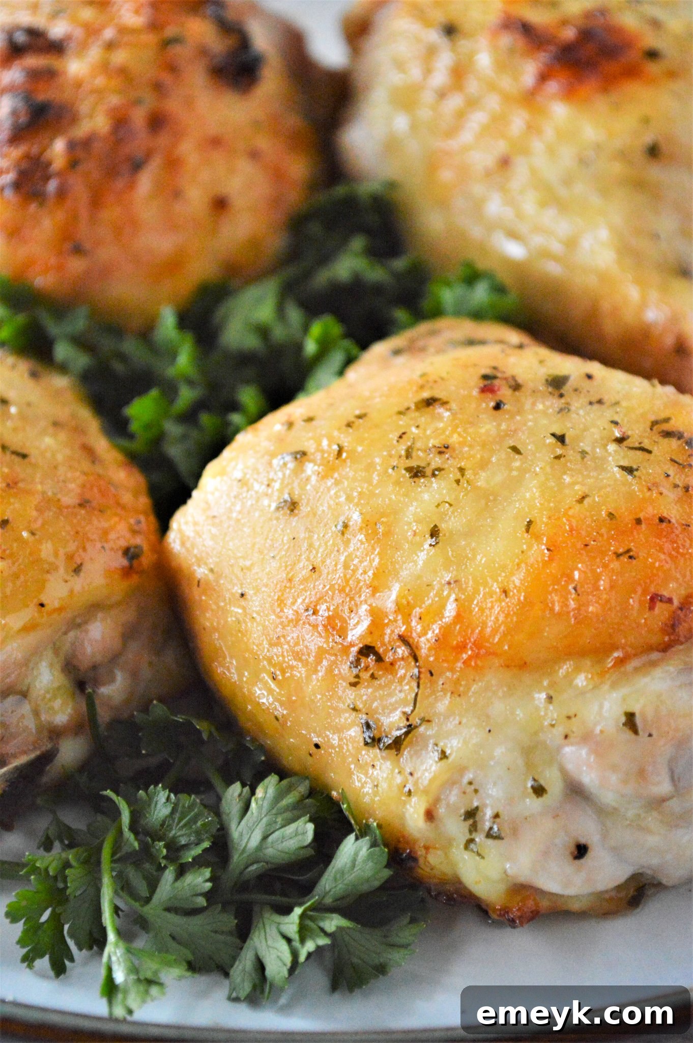 Creamy Ranch Chicken Thighs 2 Oven Baked Ranch Chicken Thighs on a plate, garnished with fresh herbs, showcasing crispy skin and tender meat.