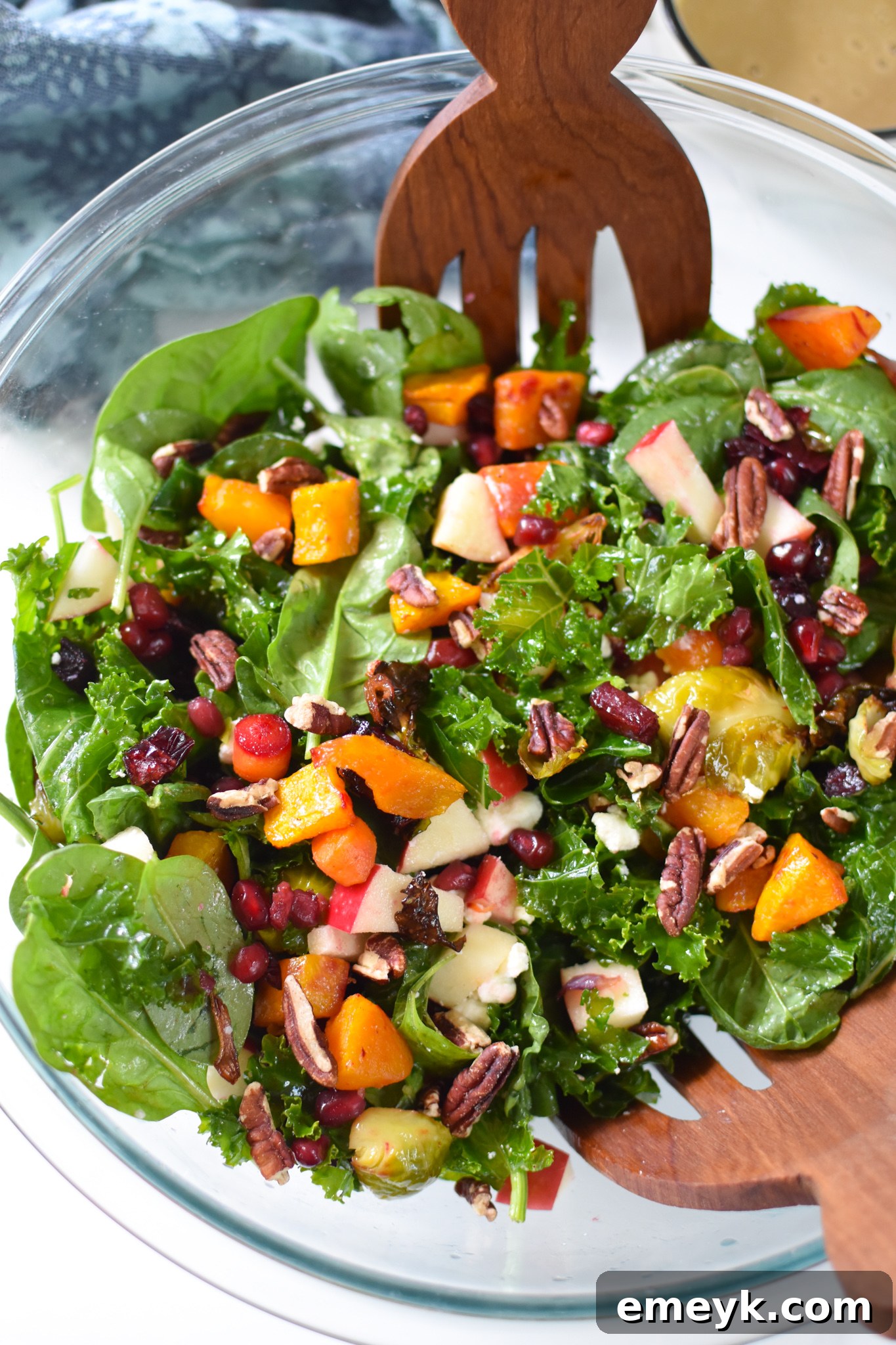 A vibrant Fall Harvest Salad in a clear glass bowl, showing off its layers of colorful ingredients.