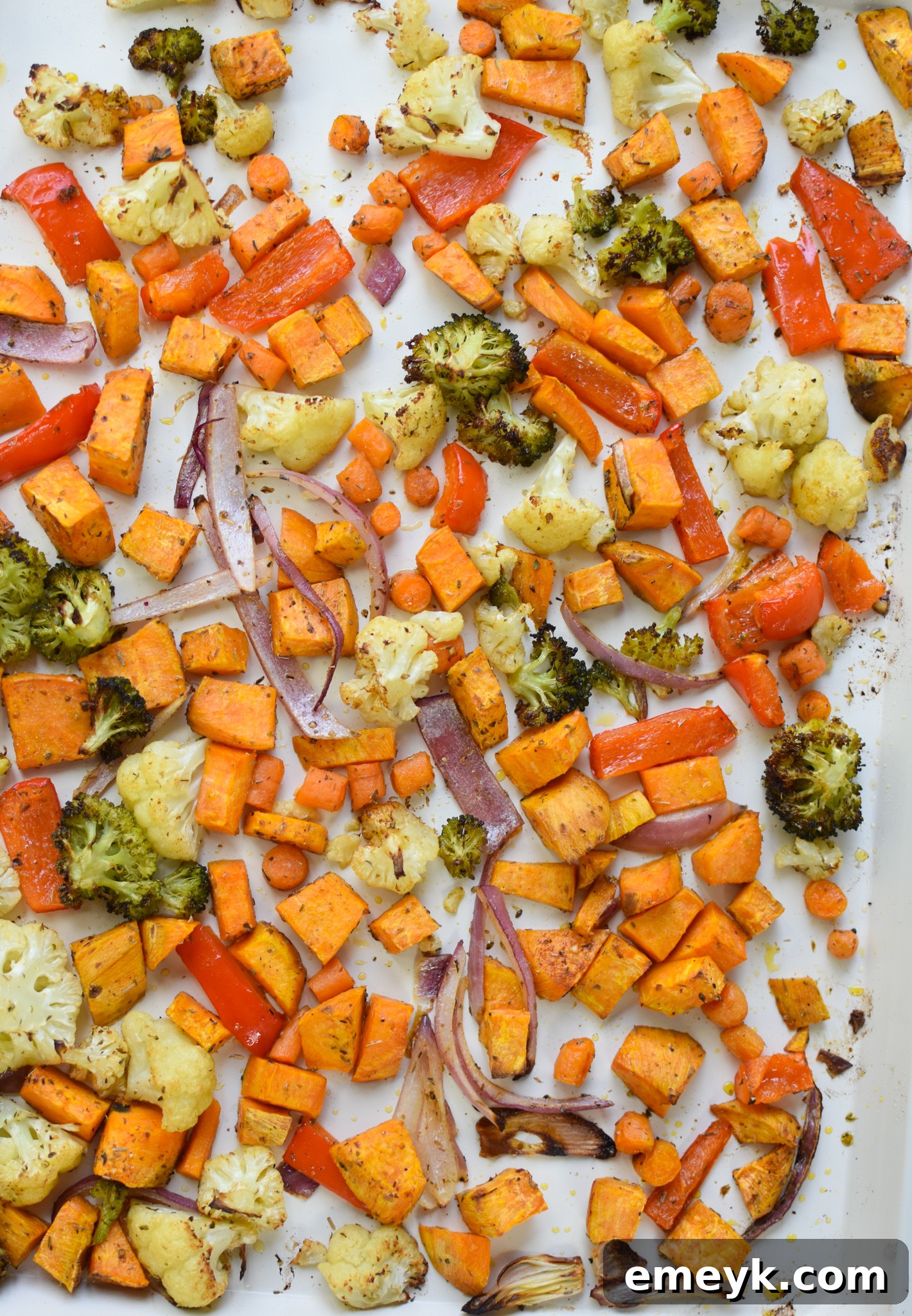 Roasted sweet potatoes and vegetables on a baking tray, showing their tender, caramelized texture after cooking.