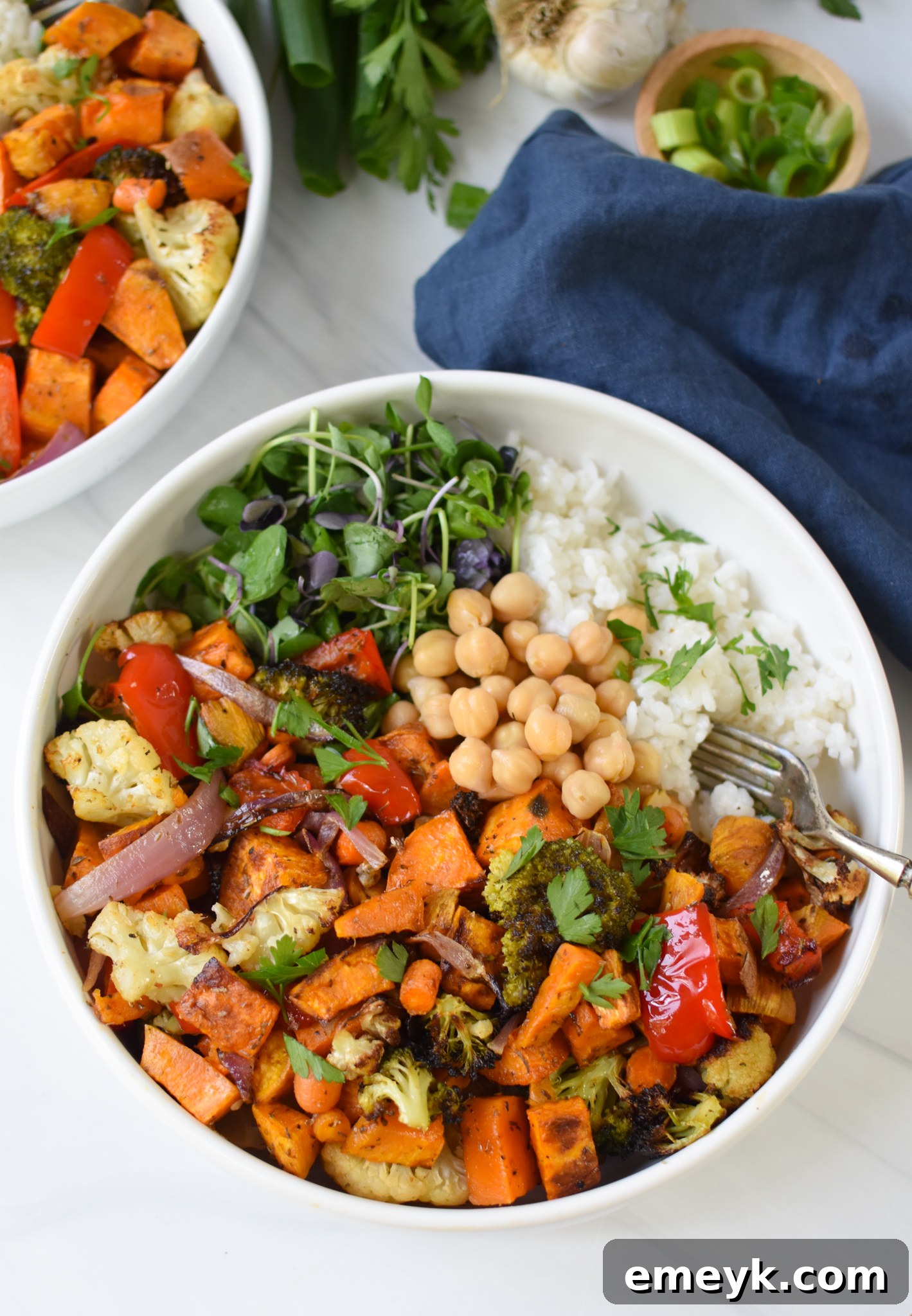 A close-up of chickpeas and fresh herbs being added to a Sweet Potato Bowl, highlighting the protein and fresh elements.