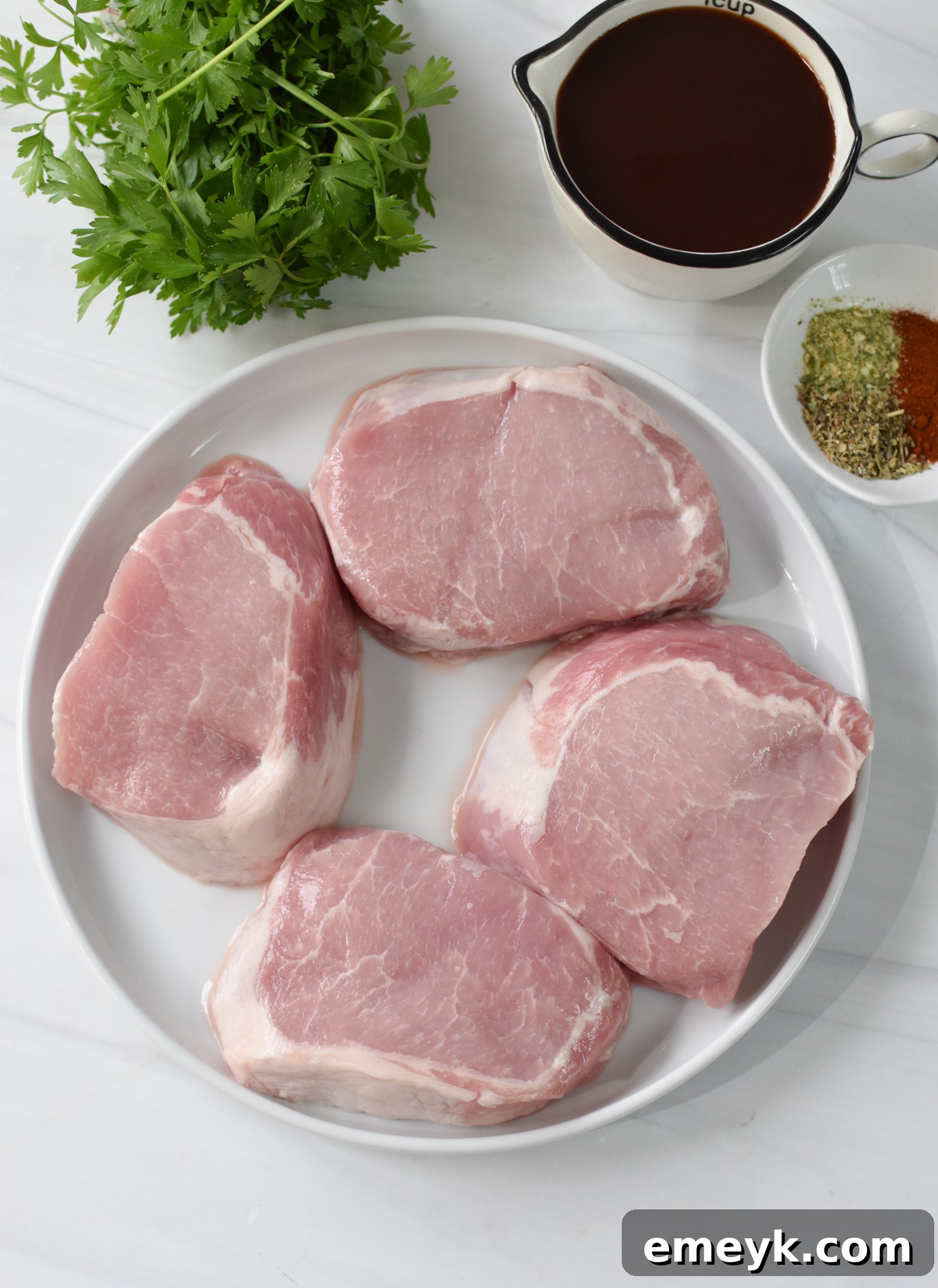 Ingredients for Air Fryer Boneless Pork Chops laid out on a wooden board.
