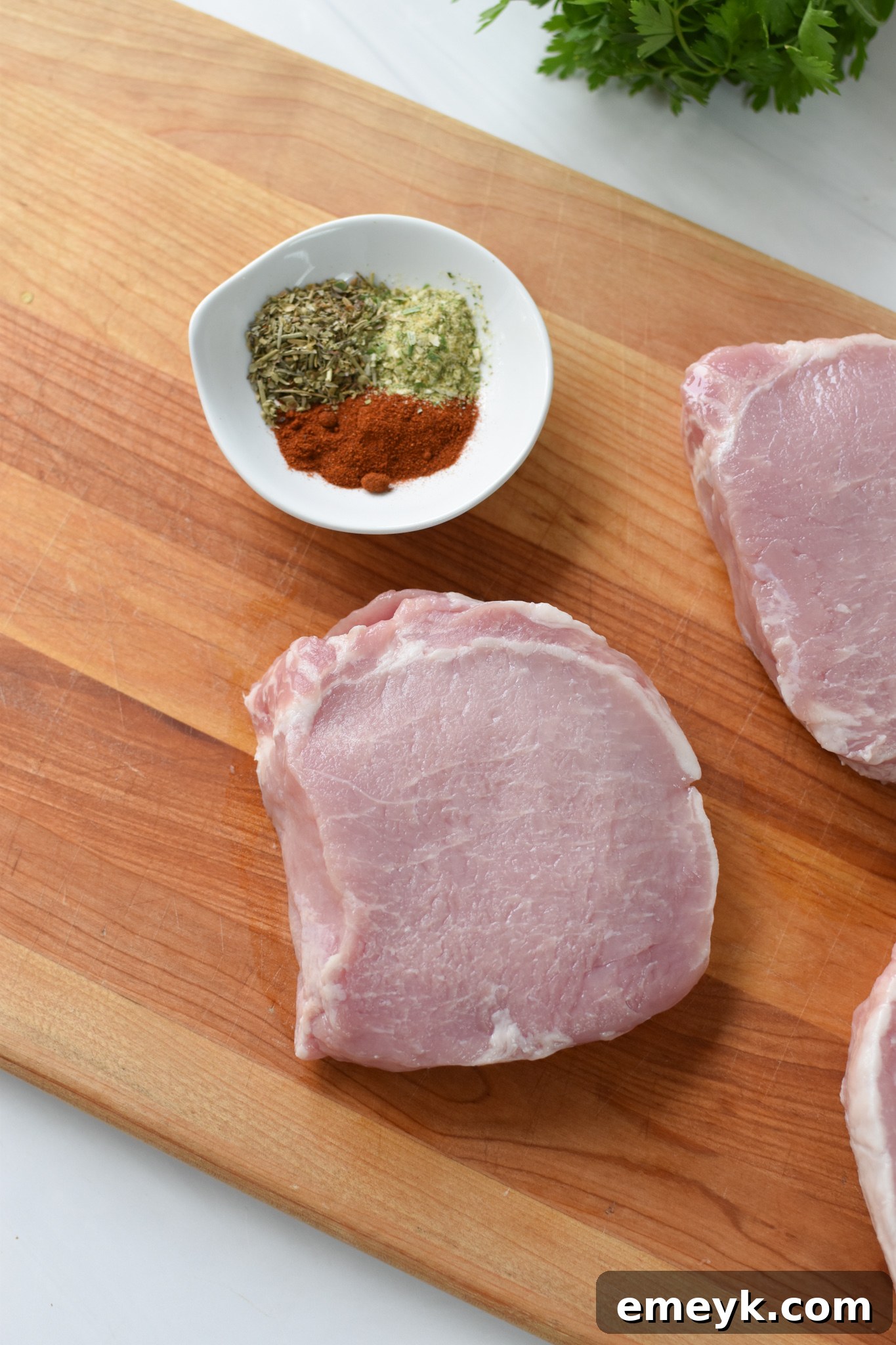 Boneless pork chops seasoned on a cutting board.