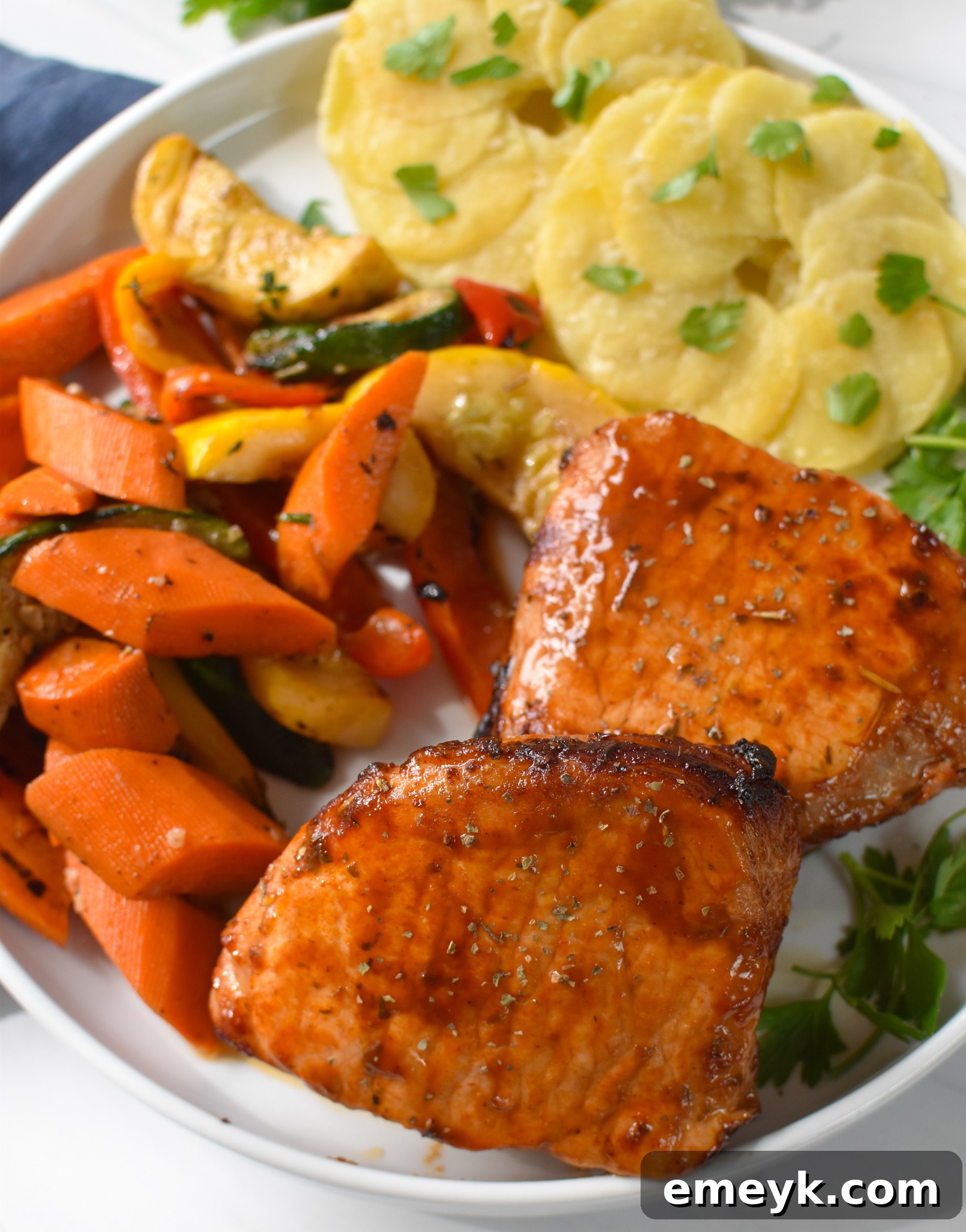 Air Fryer Boneless Pork Chops served with roasted vegetables and potatoes on a plate.