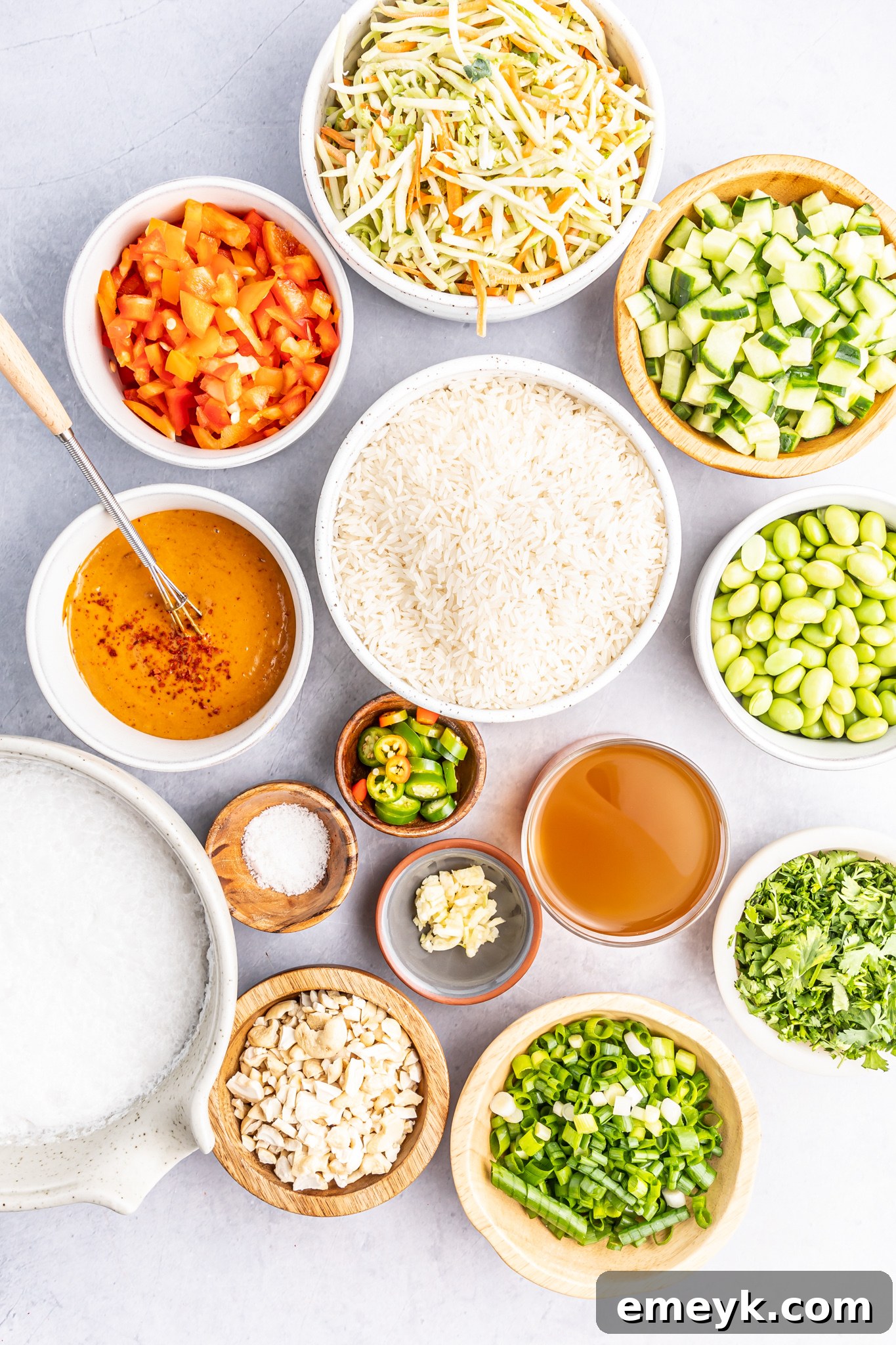 A collection of fresh ingredients laid out, including rice, coconut milk, bell pepper, edamame, and herbs, ready for the Coconut Rice Salad.