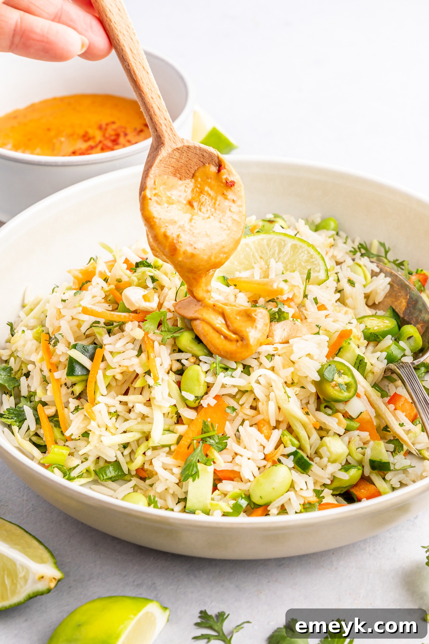 Peanut dressing being drizzled over the colorful Coconut Rice Salad, enhancing its flavors.