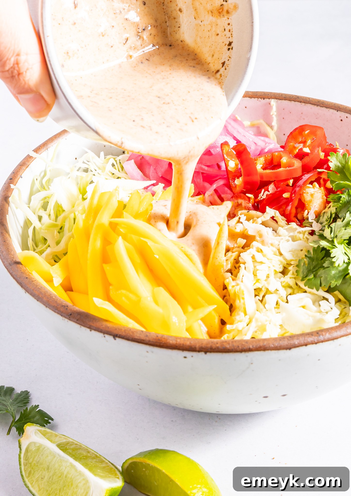 Easy Caribbean Coleslaw being drizzled generously with its creamy, tropical dressing.