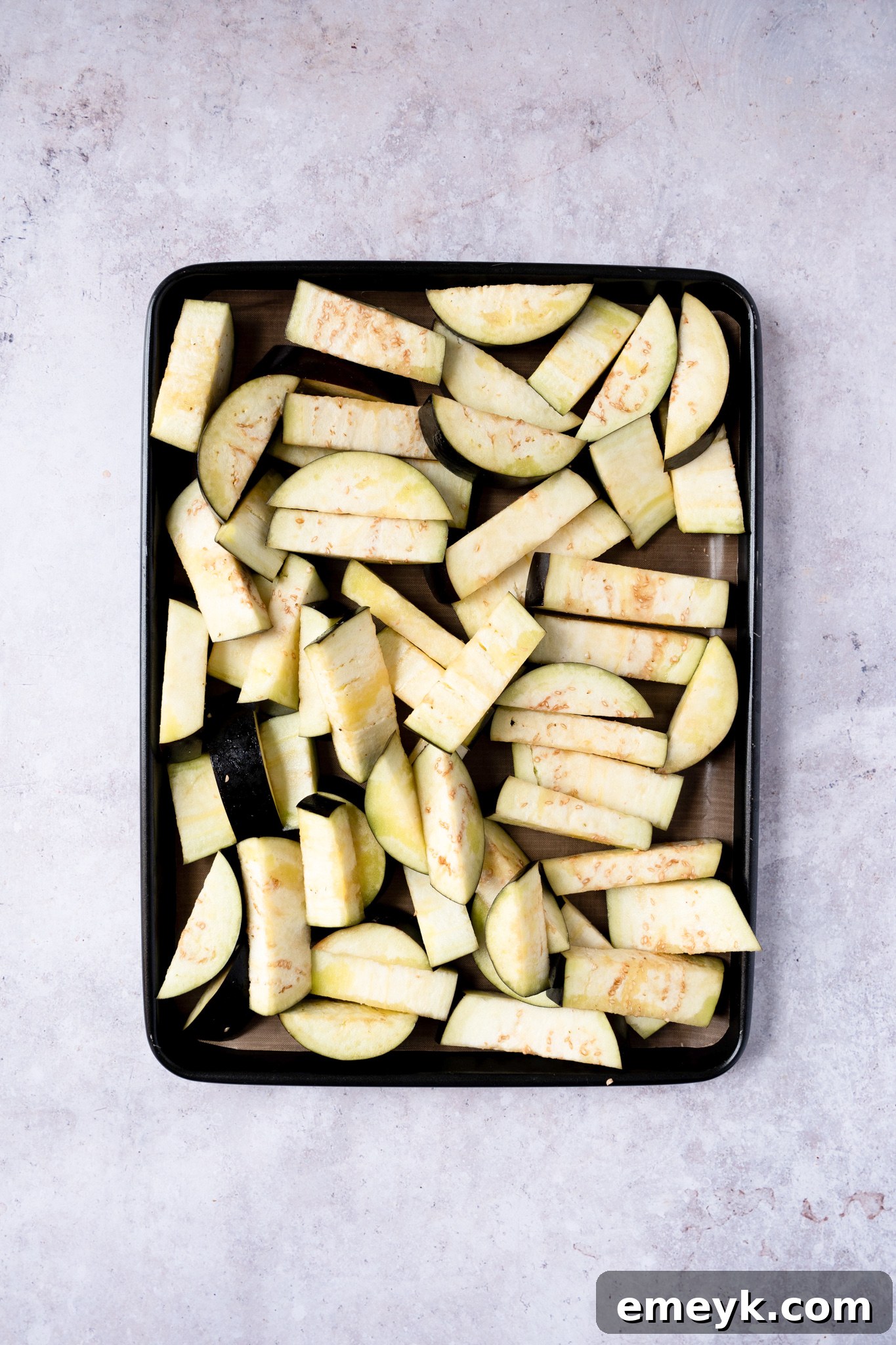 Weeknight Eggplant Wonder 5 Prepared eggplant halves seasoned with olive oil, salt, and pepper on a baking sheet, ready for roasting.