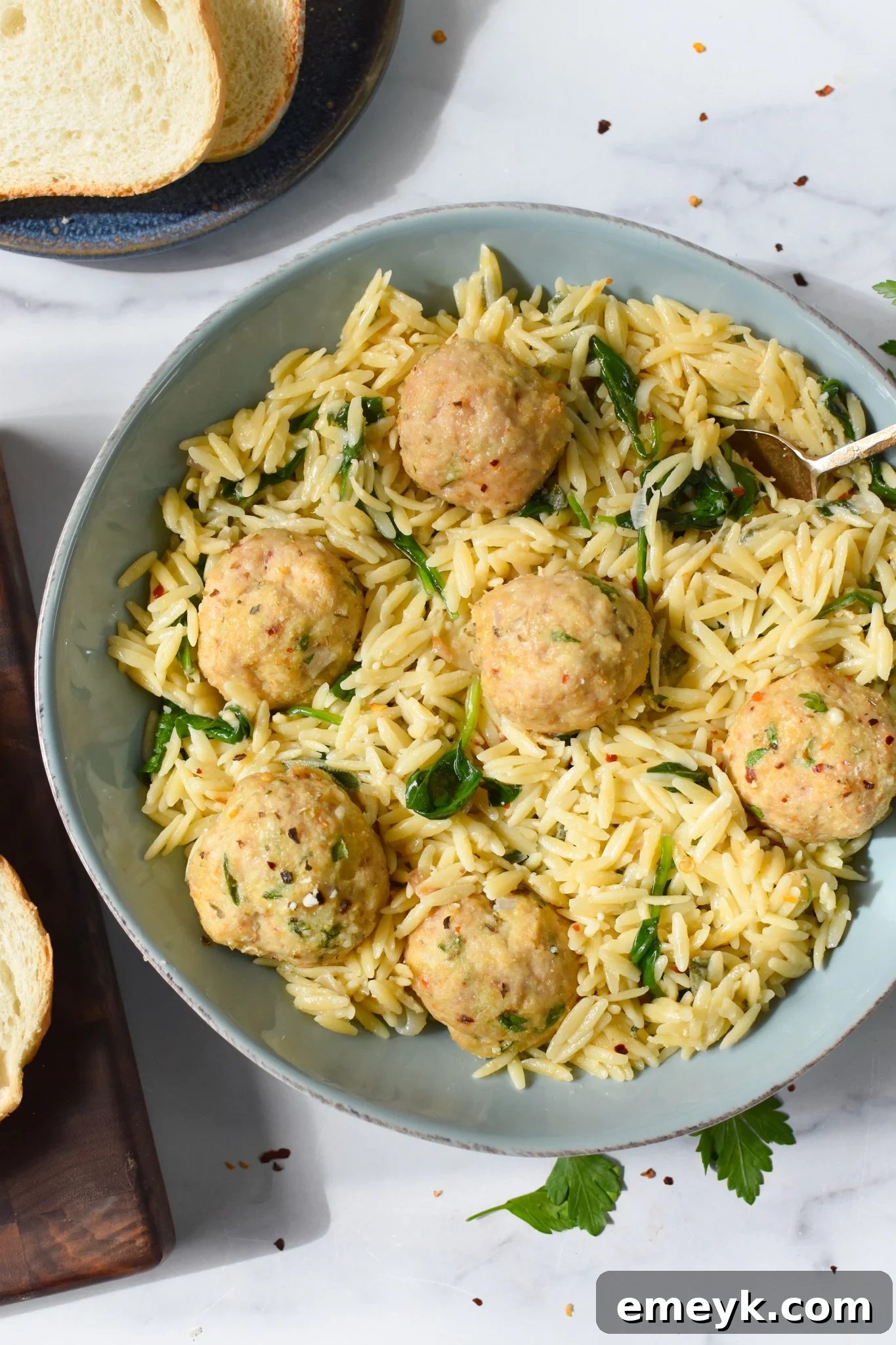 Baked Chicken Meatballs in a blue bowl. Ready to be served with creamy orzo for a comforting meal.