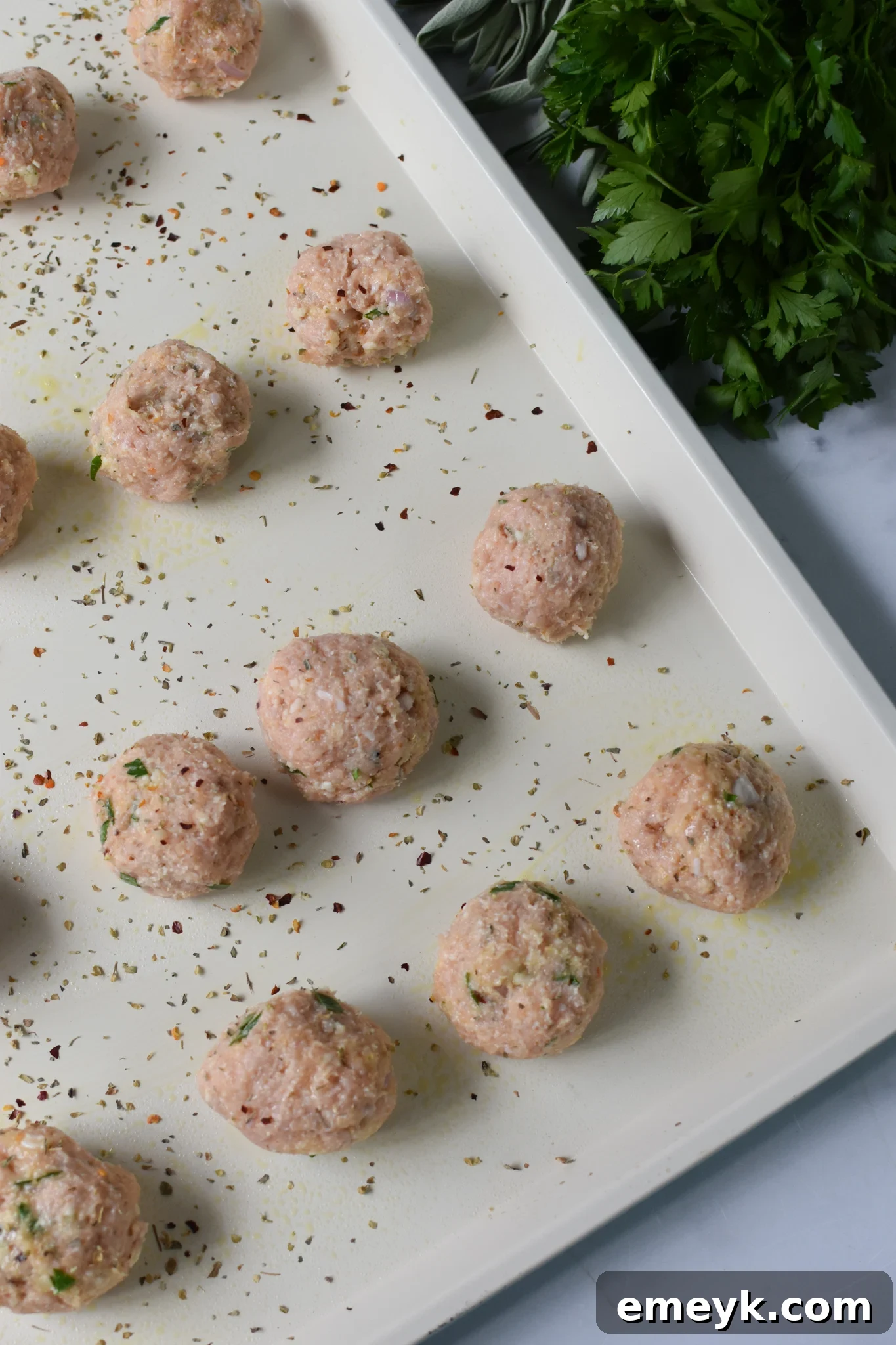 Baked Chicken Meatballs on a baking sheet. Perfectly rolled and spaced, they are now ready for the oven to transform them.