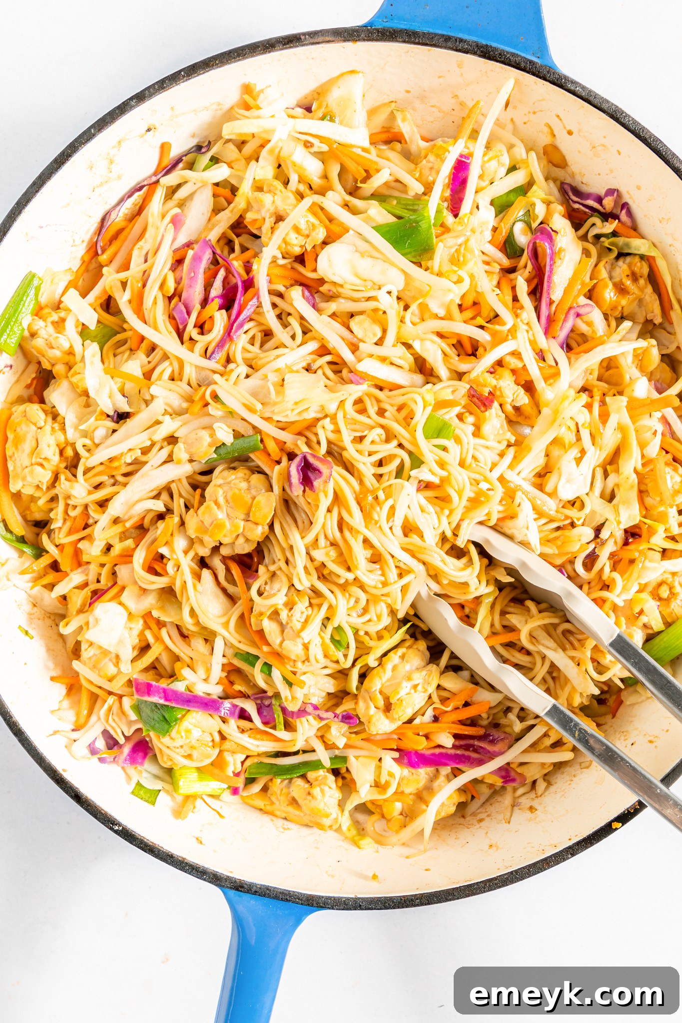 Wholesome Weeknight Veggie Chow Mein 7 Easy Vegetable Chow Mein being actively tossed with tongs in a large wok or pan, showing the dynamic cooking process.