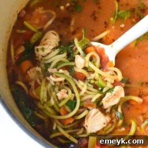 Mediterranean Fish Soup in a white bowl, garnished with fresh herbs and lime.