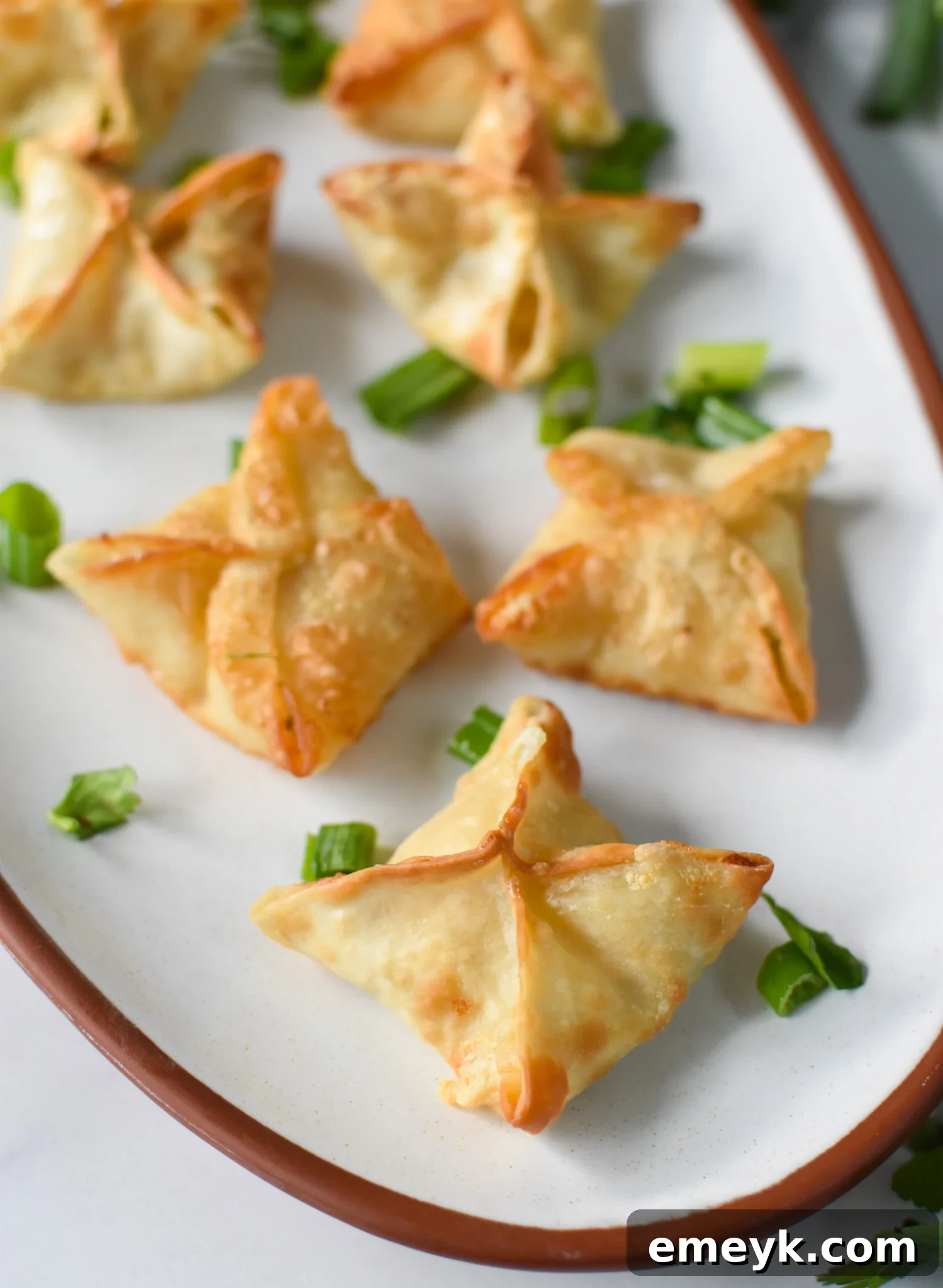 Air Fryer Crab Rangoon on a white platter, perfectly golden and crispy.