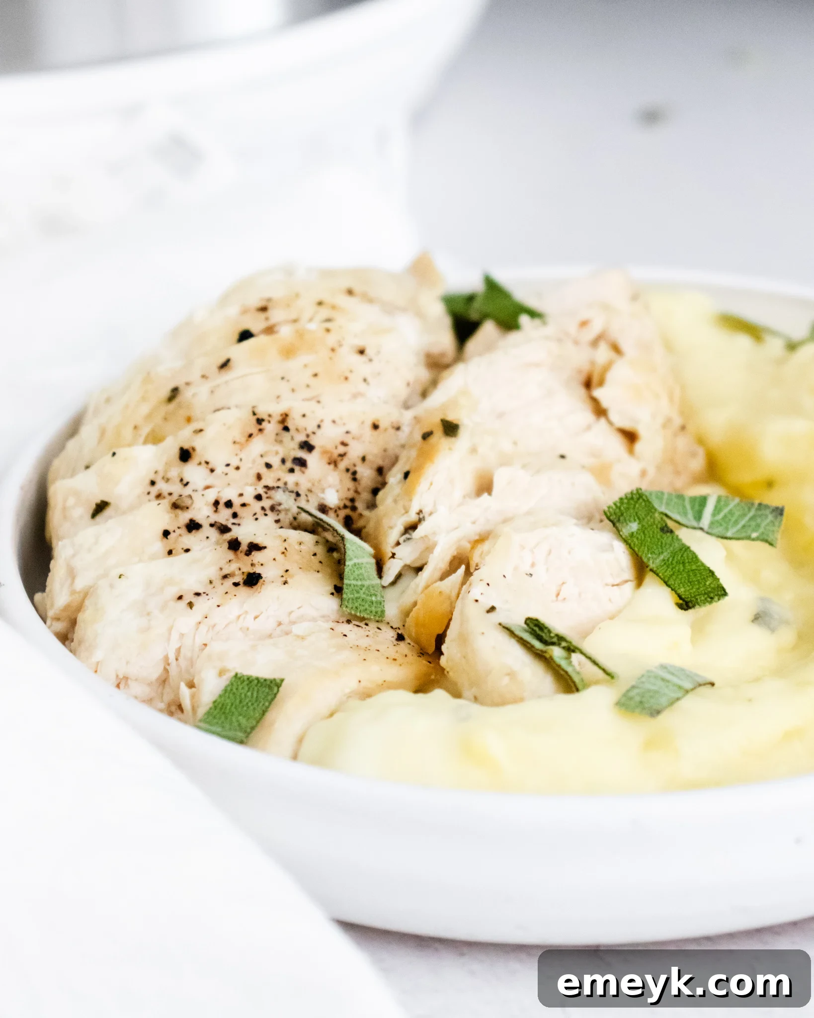 Instant Pot Chicken Breast Recipe in a white bowl, garnished with fresh herbs.
