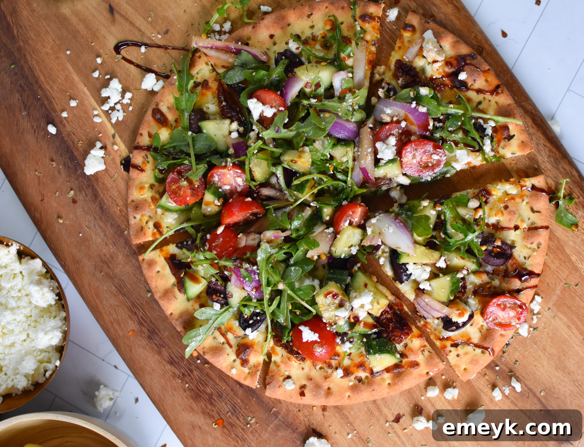 Hellenic Pizza 4 A freshly baked Greek Pizza being sliced on a cutting board, topped with a colorful salad.