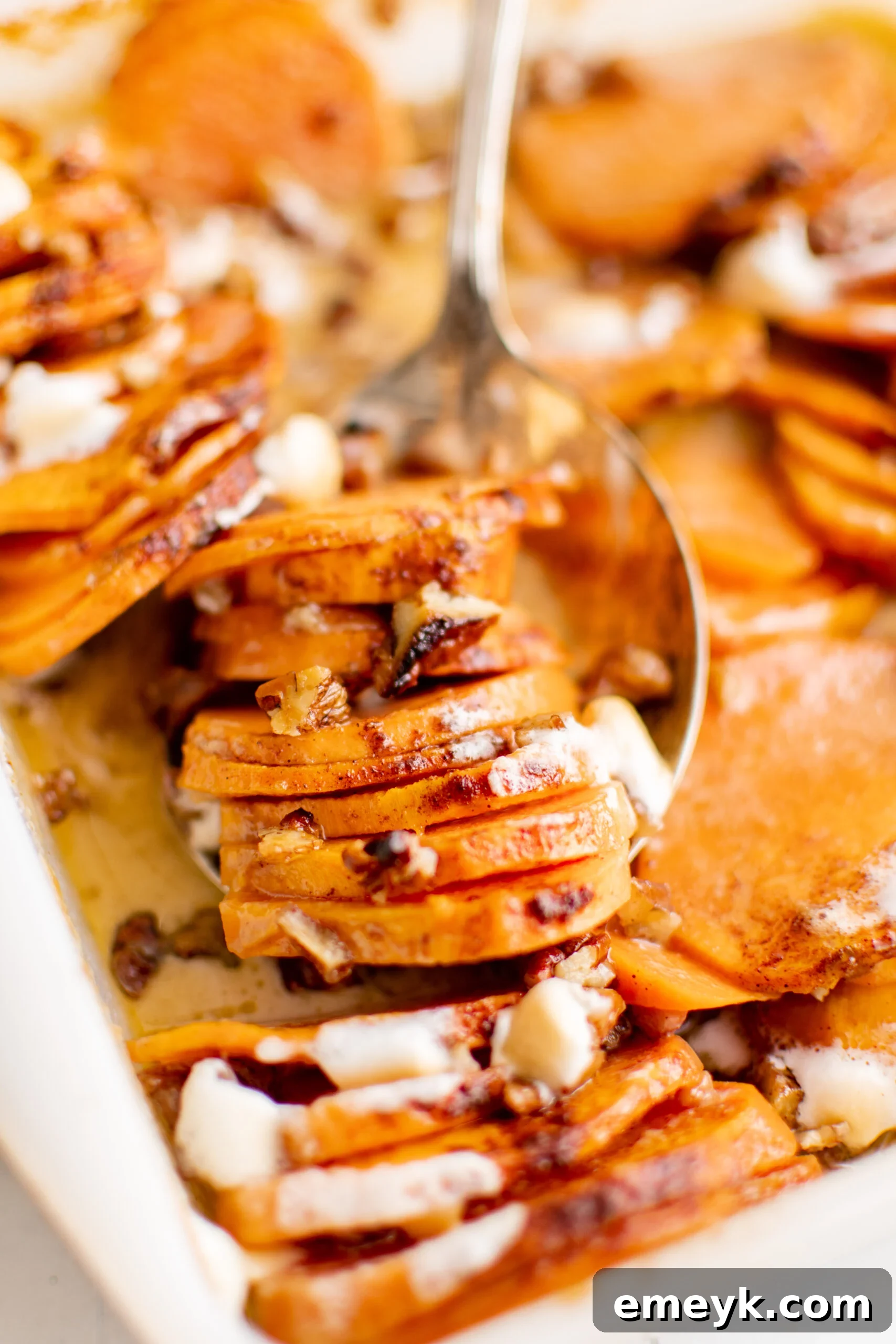 Easy Scalloped Sweet Potatoes with a serving spoon, ready to be dished out.