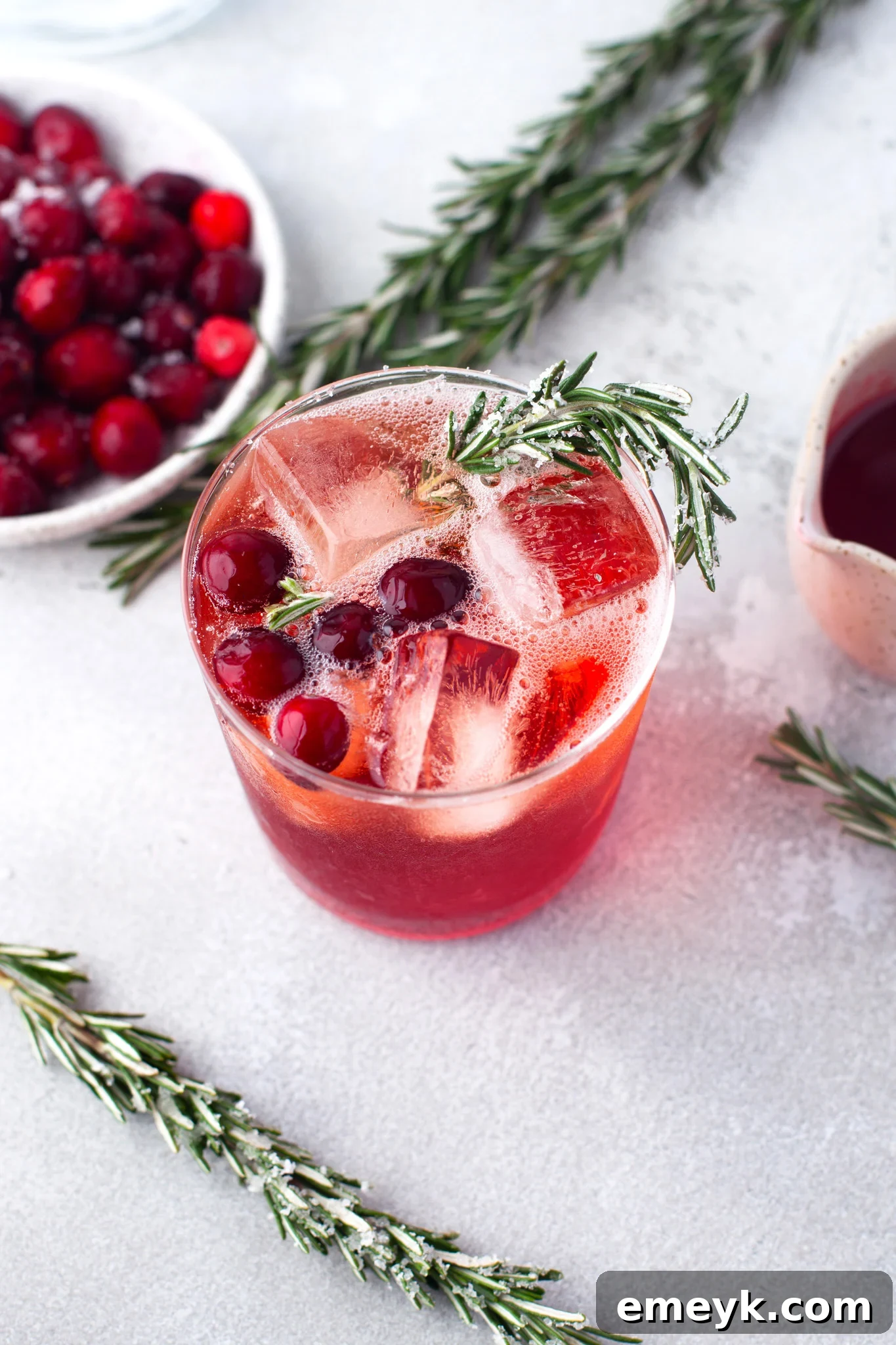 A festive Cranberry Aperol Spritz, elegantly garnished with a sprig of fresh rosemary, highlighting its winter holiday appeal.
