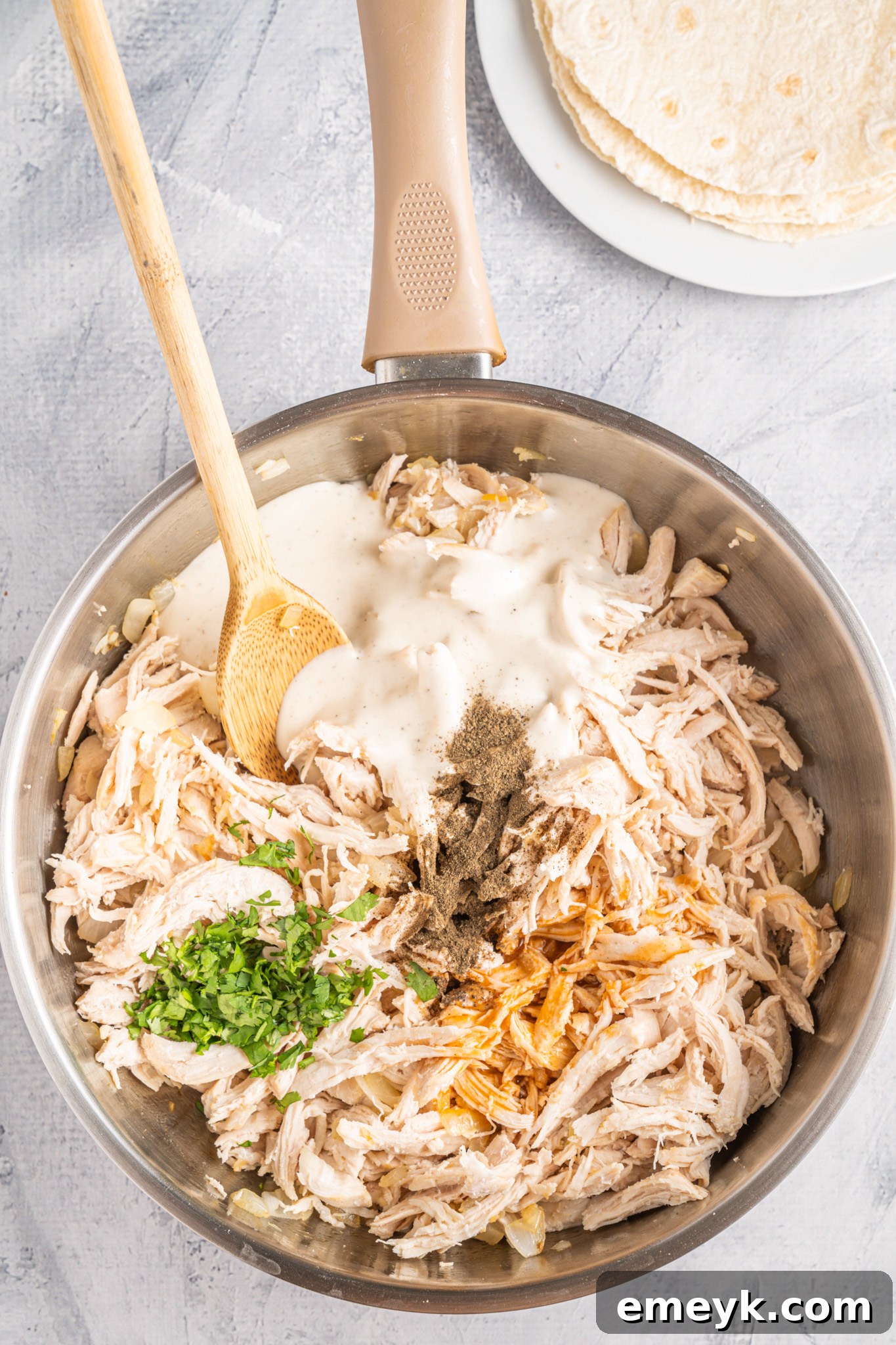 Quick Buffalo Chicken Quesadilla 6 Shredded chicken being added to the sautéed onions and garlic in a skillet