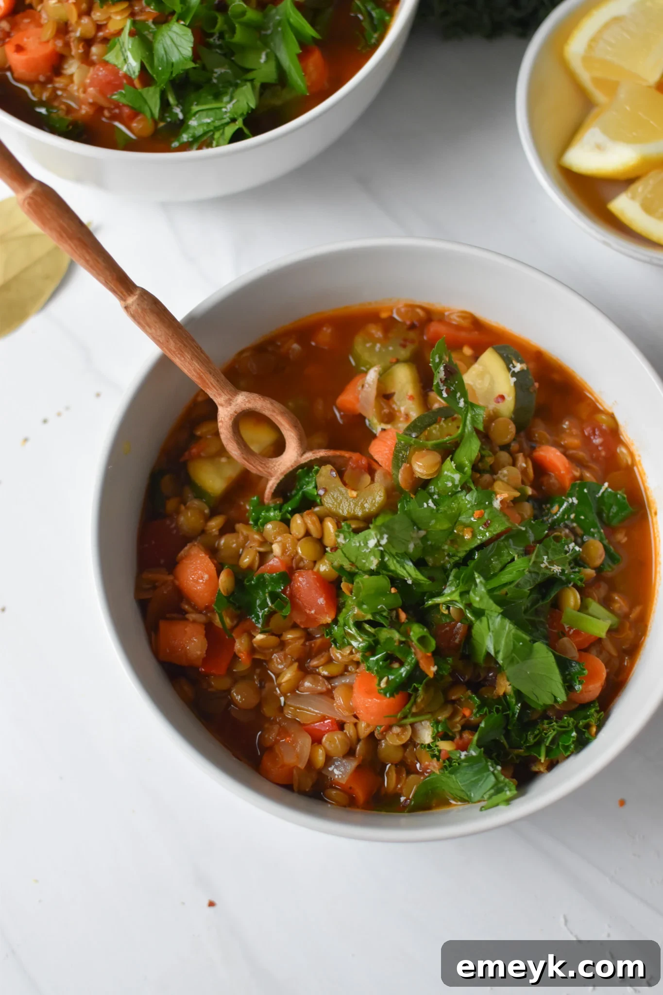 Italian Style Lentil Soup in a bowl with a wooden spoon, showcasing its texture.