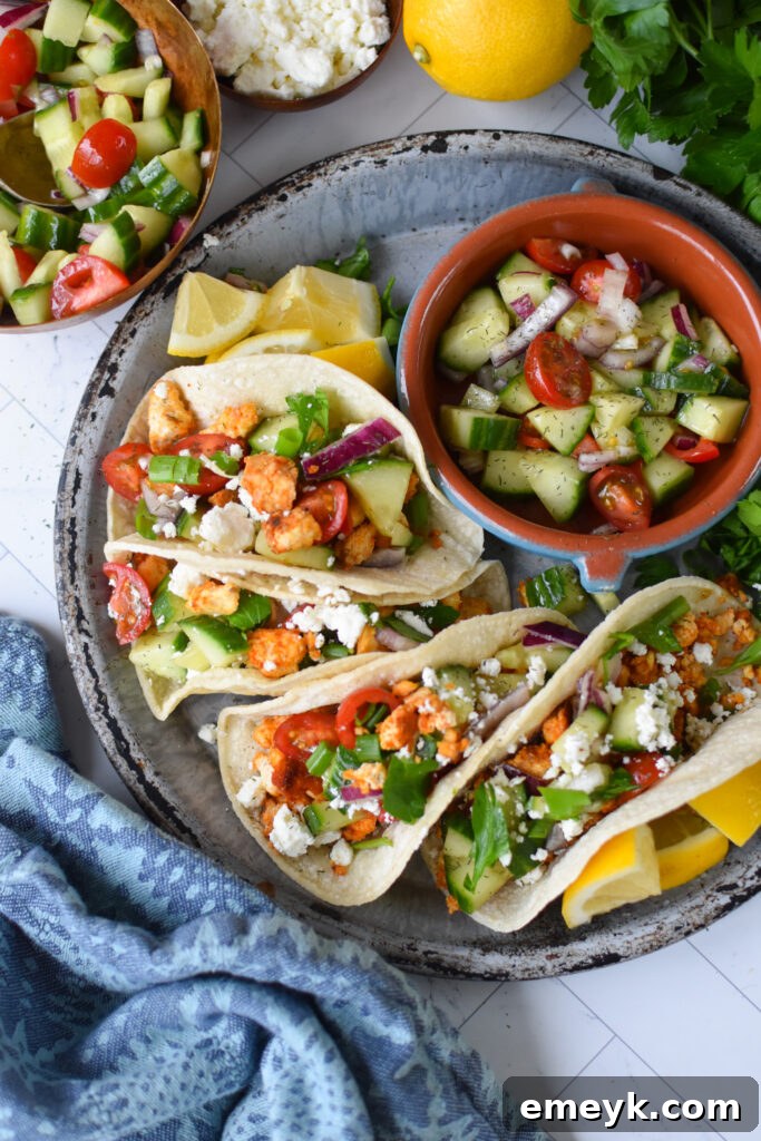 Mediterranean Style Tofu Tacos on a blue plate, garnished with fresh herbs and feta.