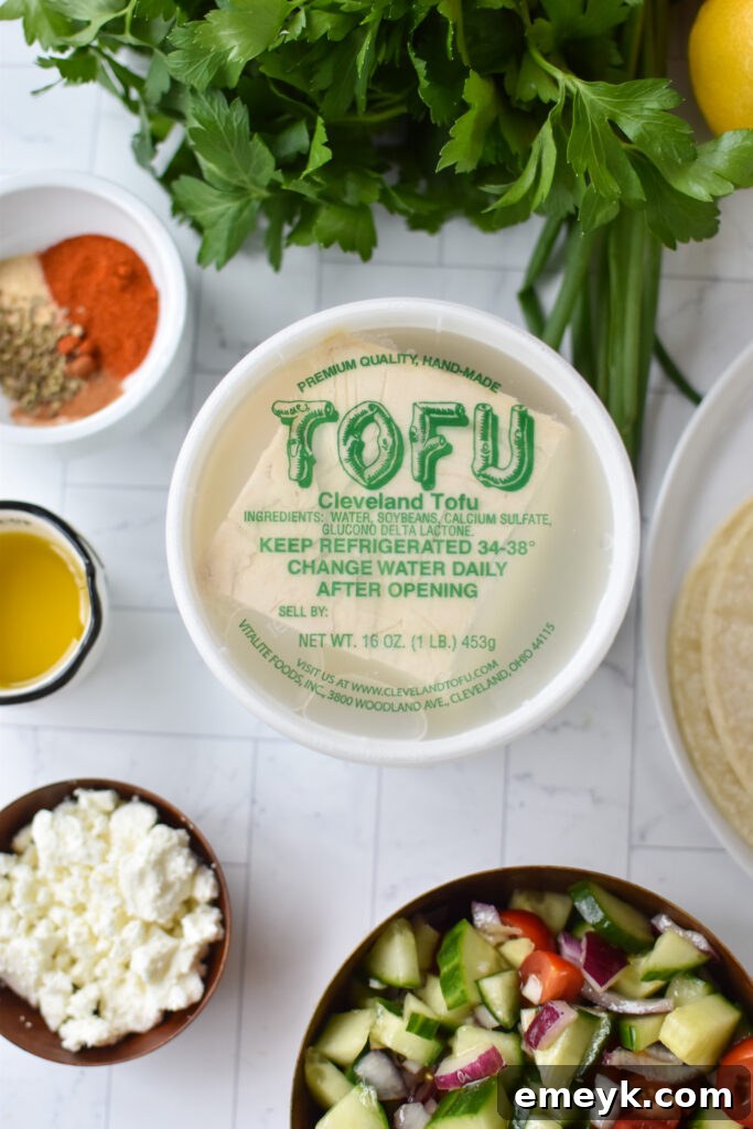 A flat lay of Mediterranean Style Tofu Tacos ingredients including tofu, spices, vegetables, and tortillas.