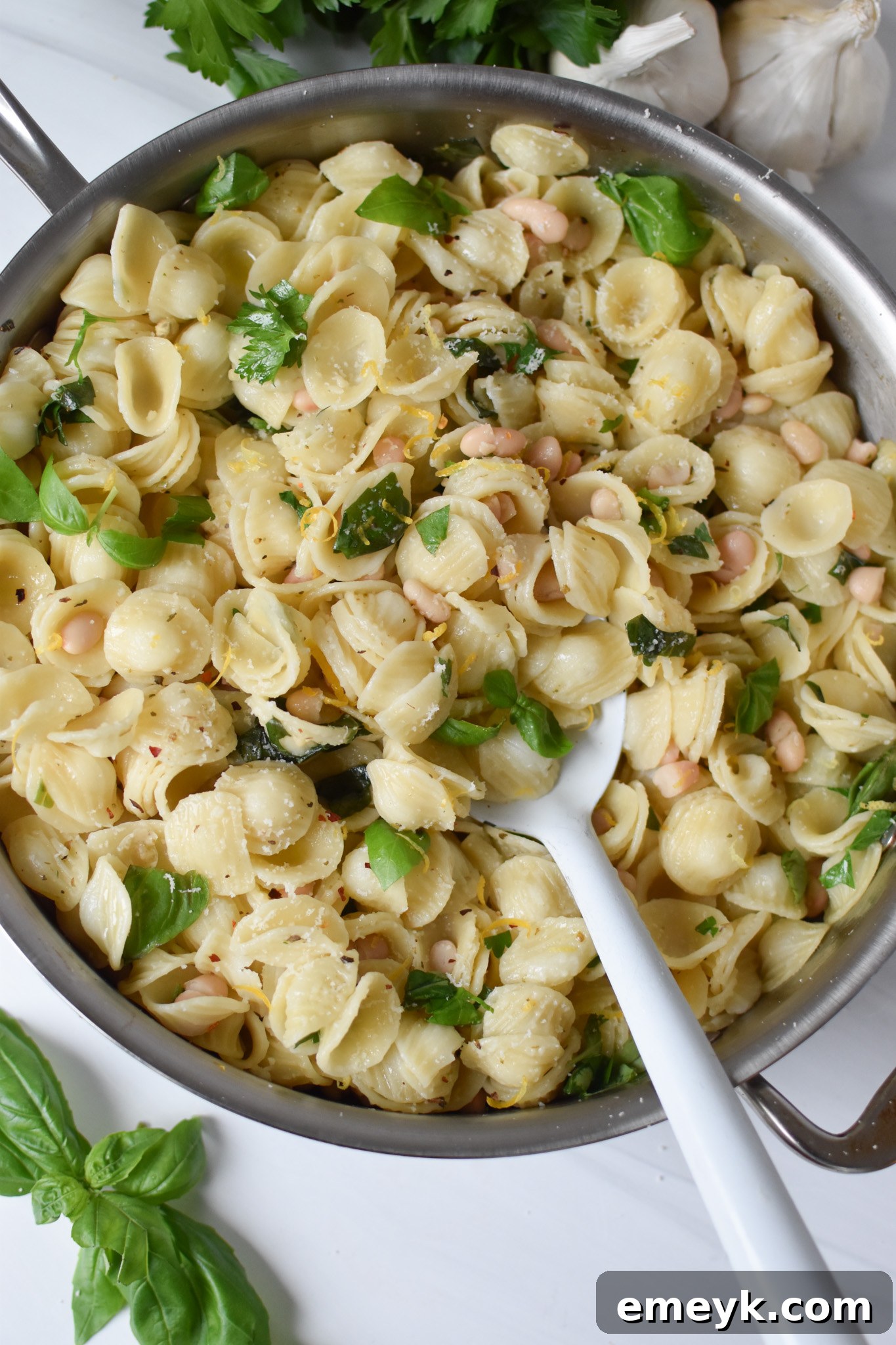 Zesty Lemon Basil White Bean Pasta 4 Lemon Basil White Bean Pasta cooking in a large skillet, with a wooden spoon mixing it.