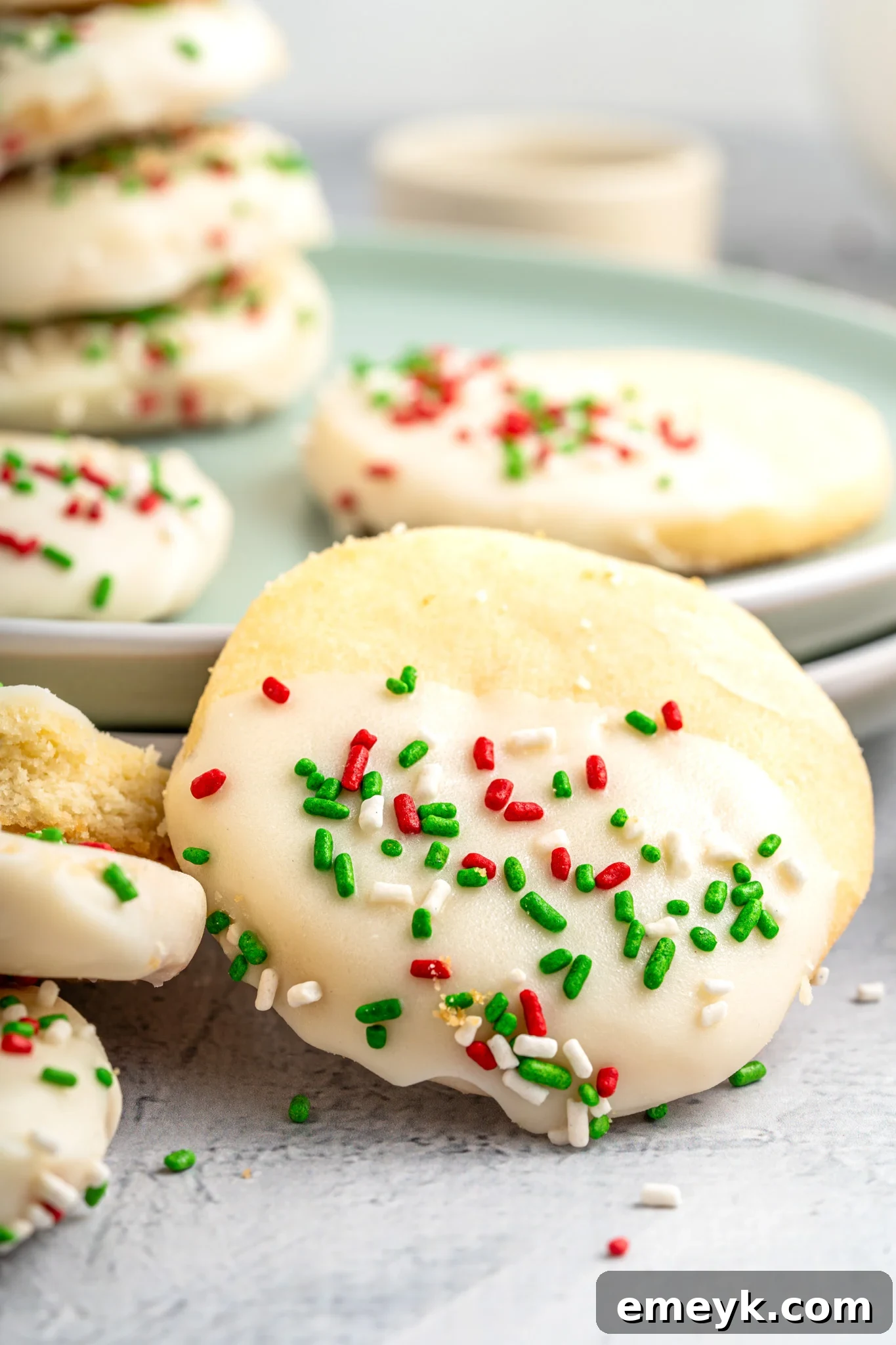 Christmas Shortbread Cookies on a green plate, beautifully decorated with white chocolate and festive sprinkles.
