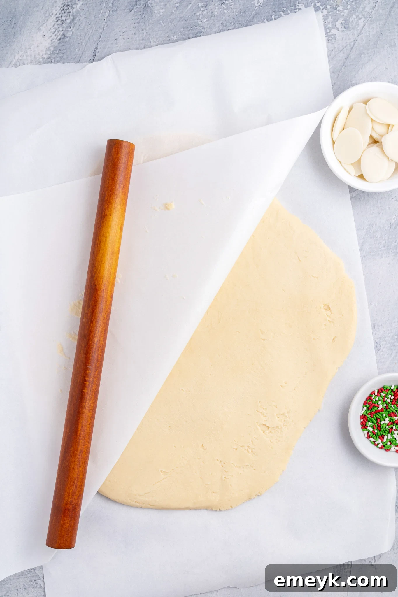 Christmas Shortbread Cookies dough being rolled between parchment paper.