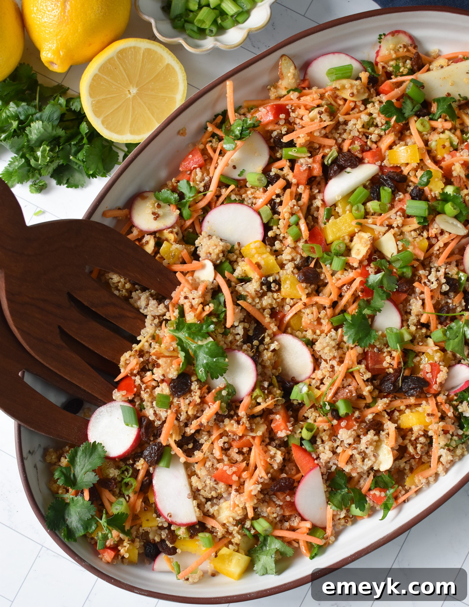 Curried Quinoa Salad with wooden tongs, ready to be served.