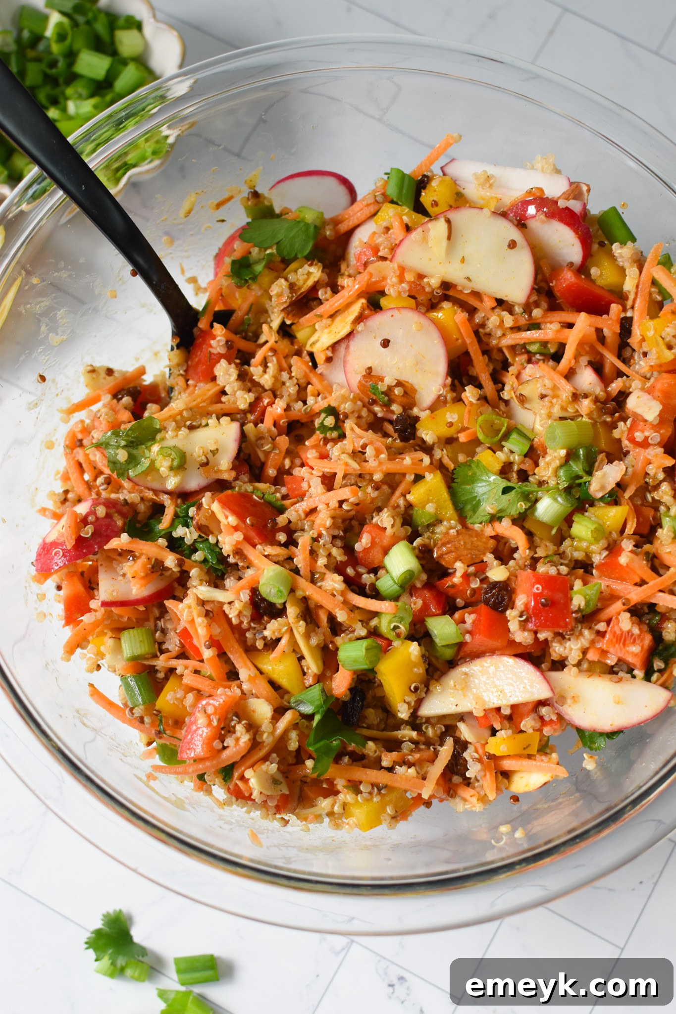 Curried Quinoa Salad ingredients mixed with dressing in a bowl.