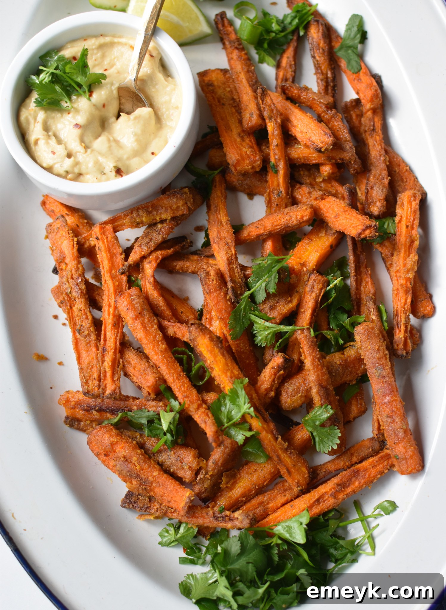Golden Roasted Carrot Fries 2 Golden-brown Oven Baked Carrot Fries served on a white oval plate, garnished with fresh herbs.