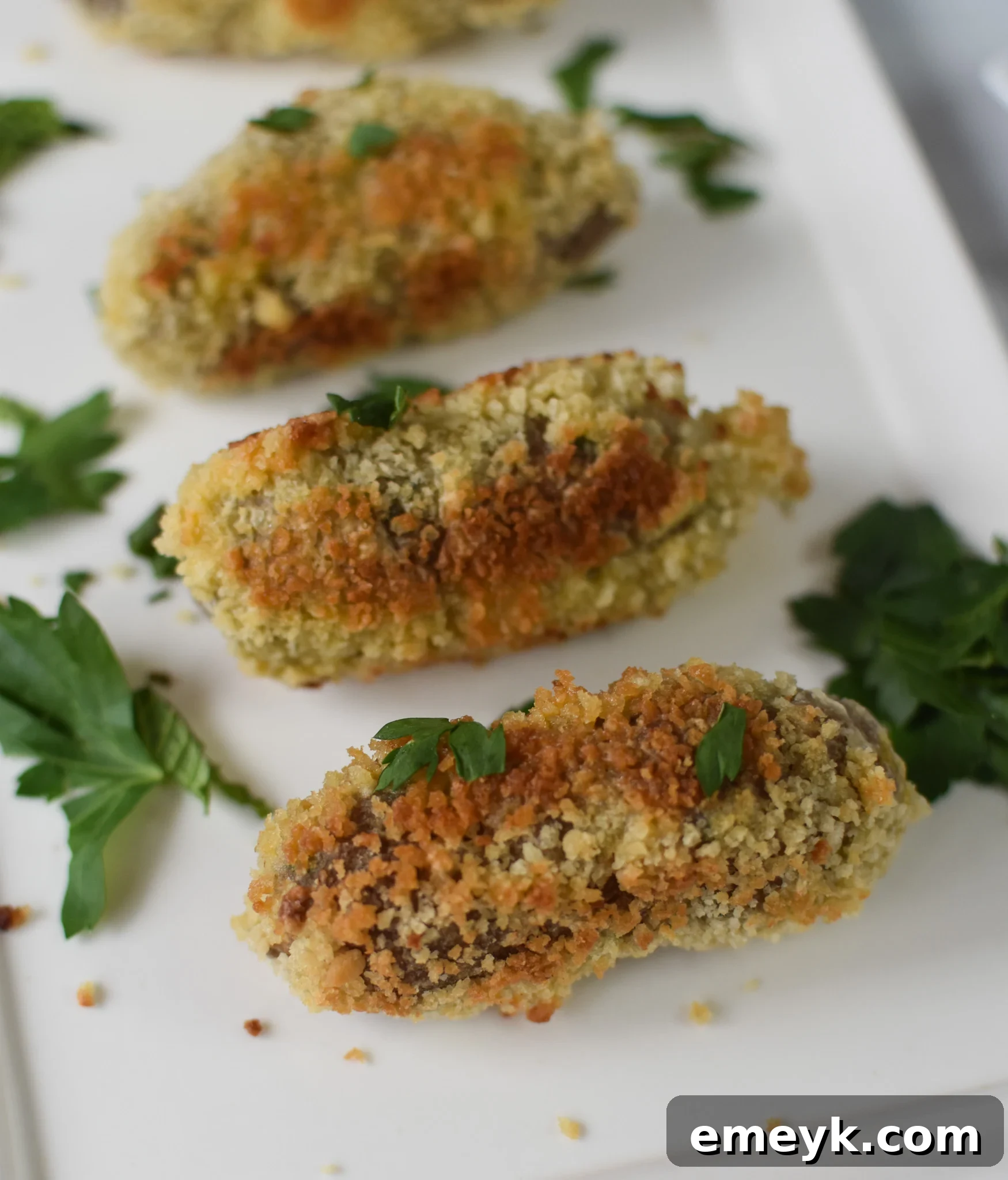 Gourmet Lamb Croquettes 2 Golden-brown crispy lamb croquettes served on a white plate, garnished with fresh herbs.