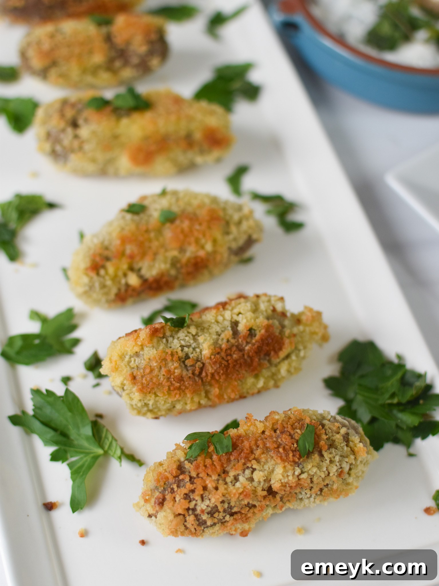 Gourmet Lamb Croquettes 8 A serving of crispy lamb croquettes presented on a white plate, garnished with fresh herbs and a side of dipping sauce.