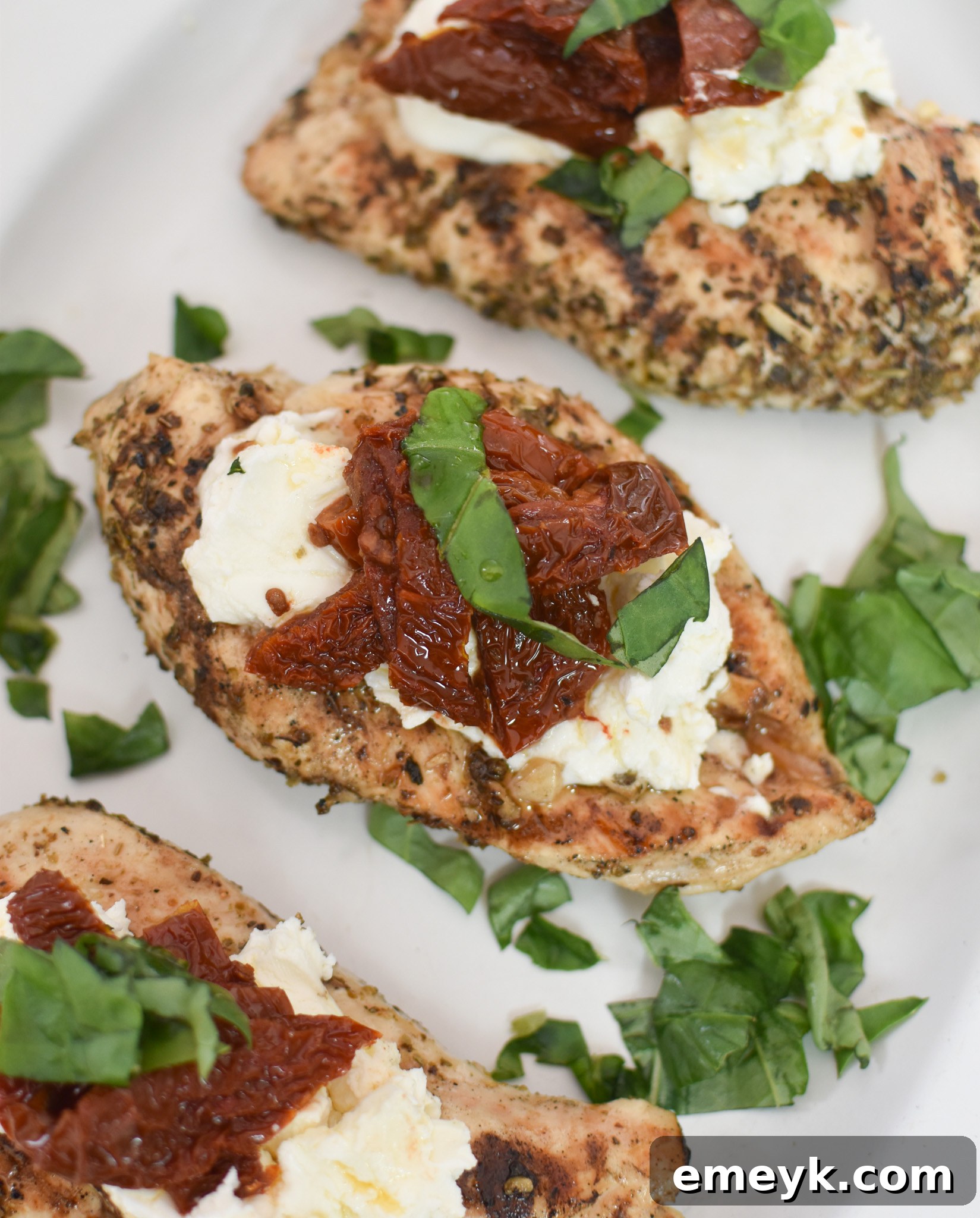 Perfectly cooked Chicken Bryan served on a white platter, garnished with fresh basil and sun-dried tomatoes.