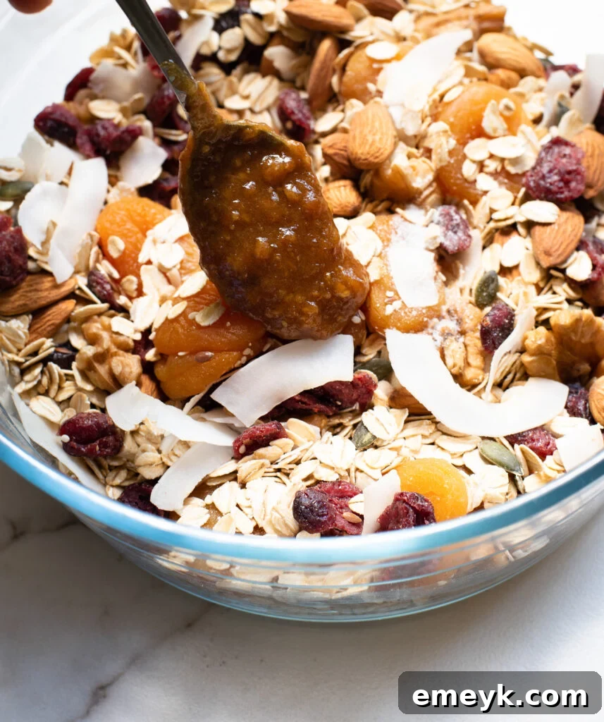 The luscious date mixture being poured over the dry ingredients in a mixing bowl, beginning the process of combining for the granola bars.