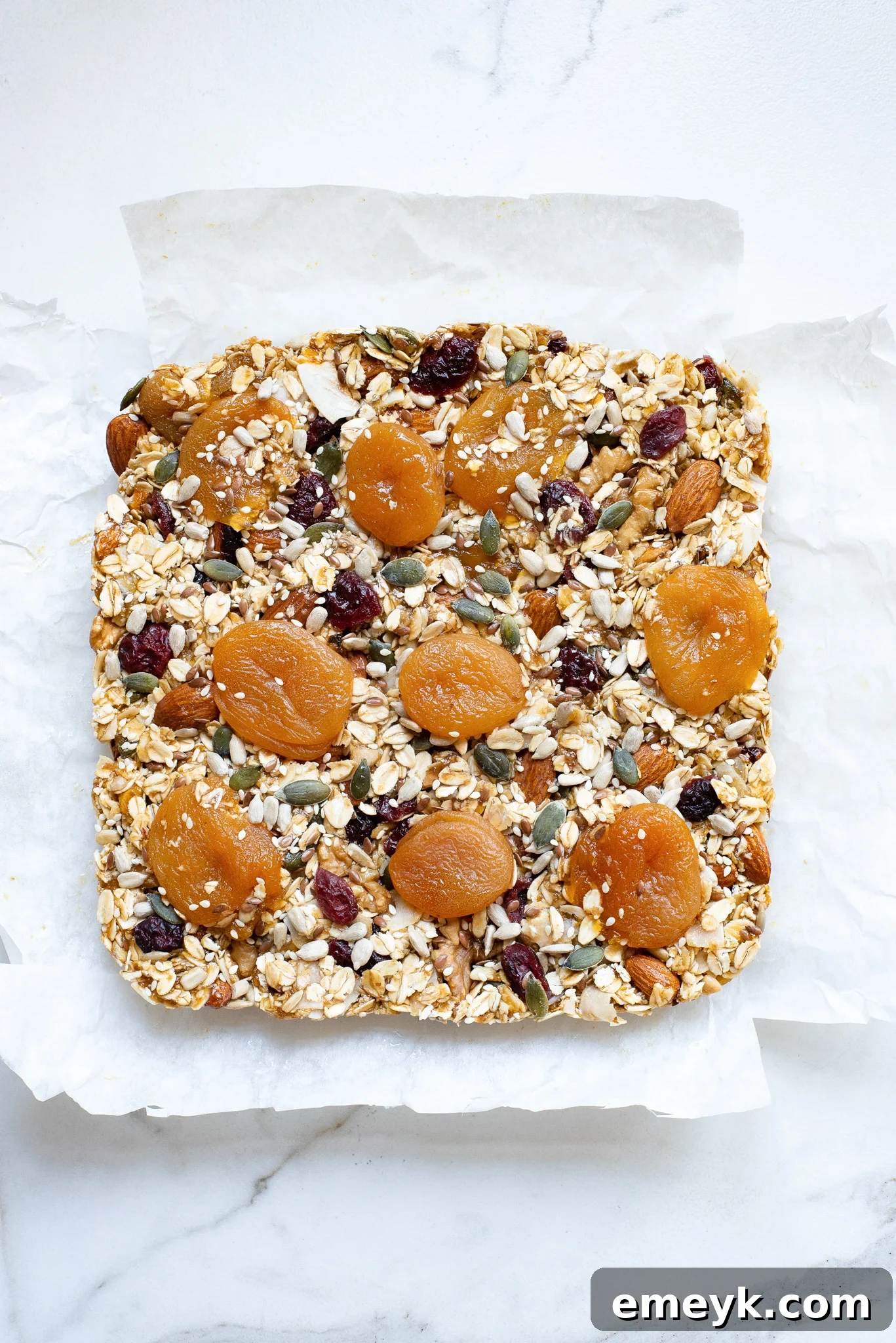 The chilled slab of easy date granola bars, lifted from the pan with parchment paper, perfectly textured and ready for precise slicing into individual portions.