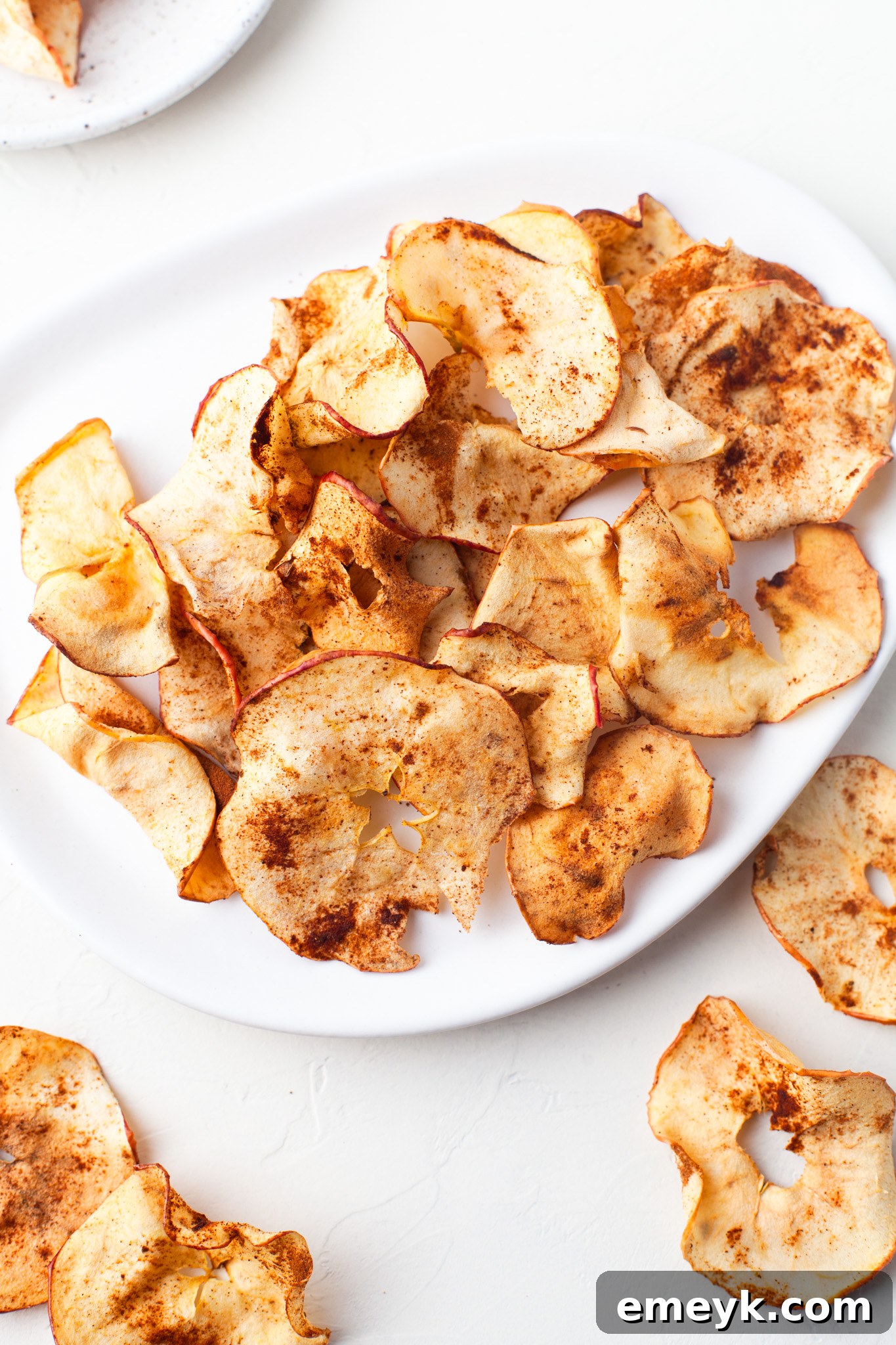 Crispy Air Fryer Apple Chips 4 Easy Air Fryer Apple Chips neatly arranged on a white plate, ready to be enjoyed.