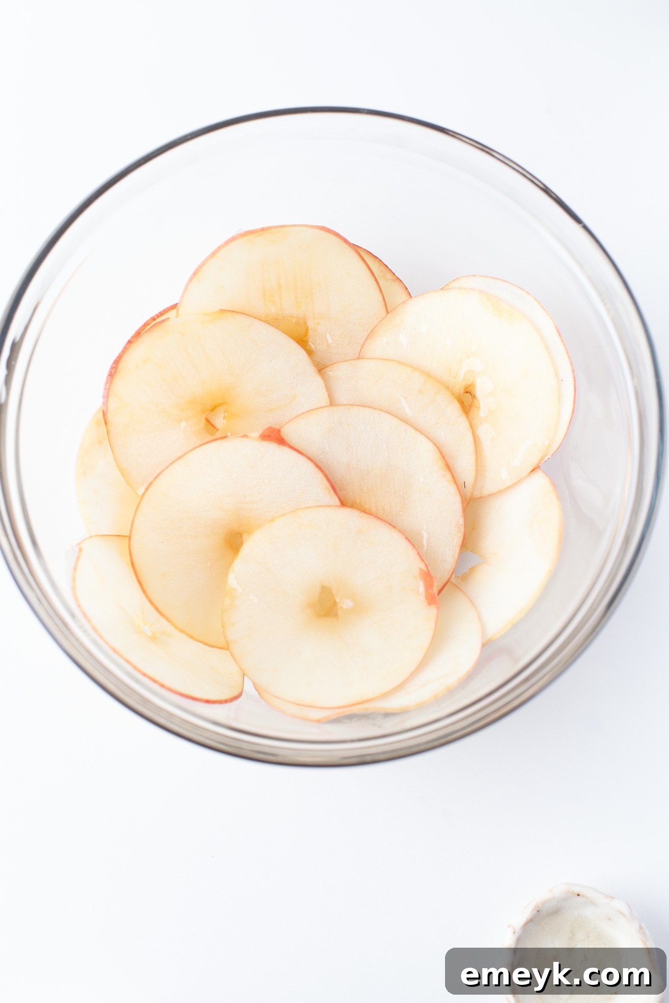 Crispy Air Fryer Apple Chips 6 Thinly sliced apples in a clear bowl, ready for seasoning.