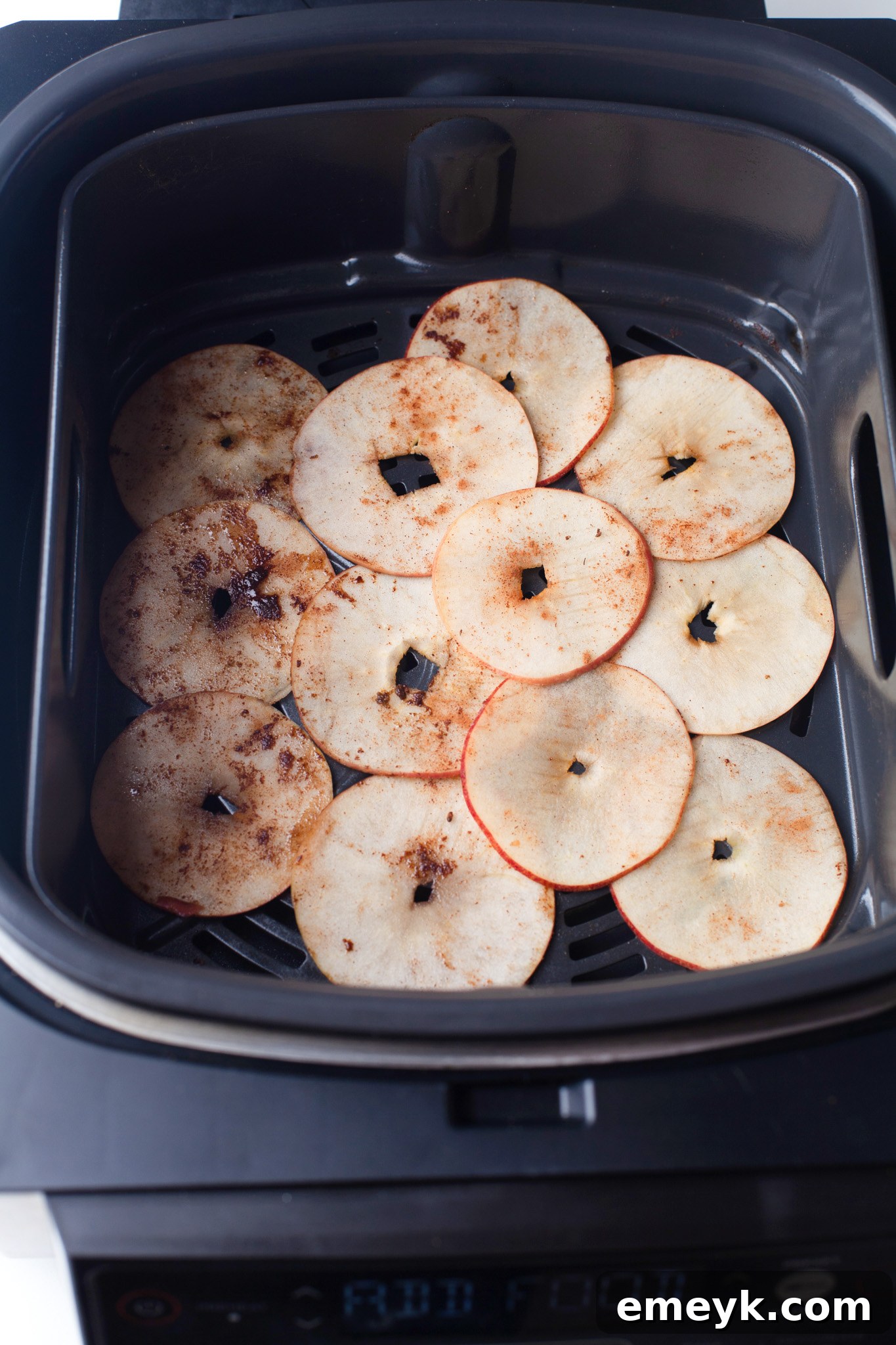 Crispy Air Fryer Apple Chips 8 Apple slices cooking inside an air fryer basket, turning golden brown.