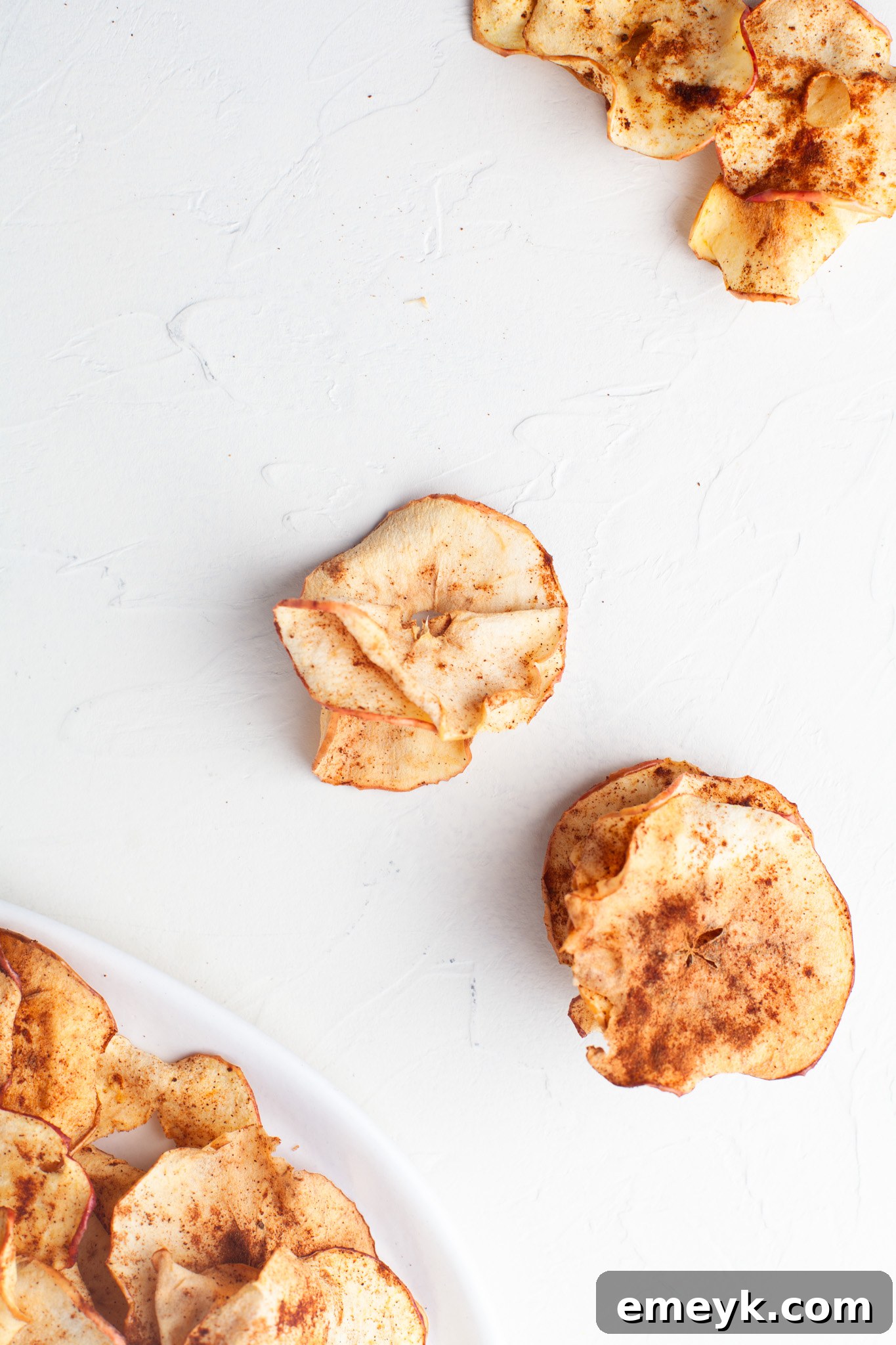 Crispy Air Fryer Apple Chips 10 Air Fryer Apple Chips beautifully arranged on a white table, showcasing their golden crispness.