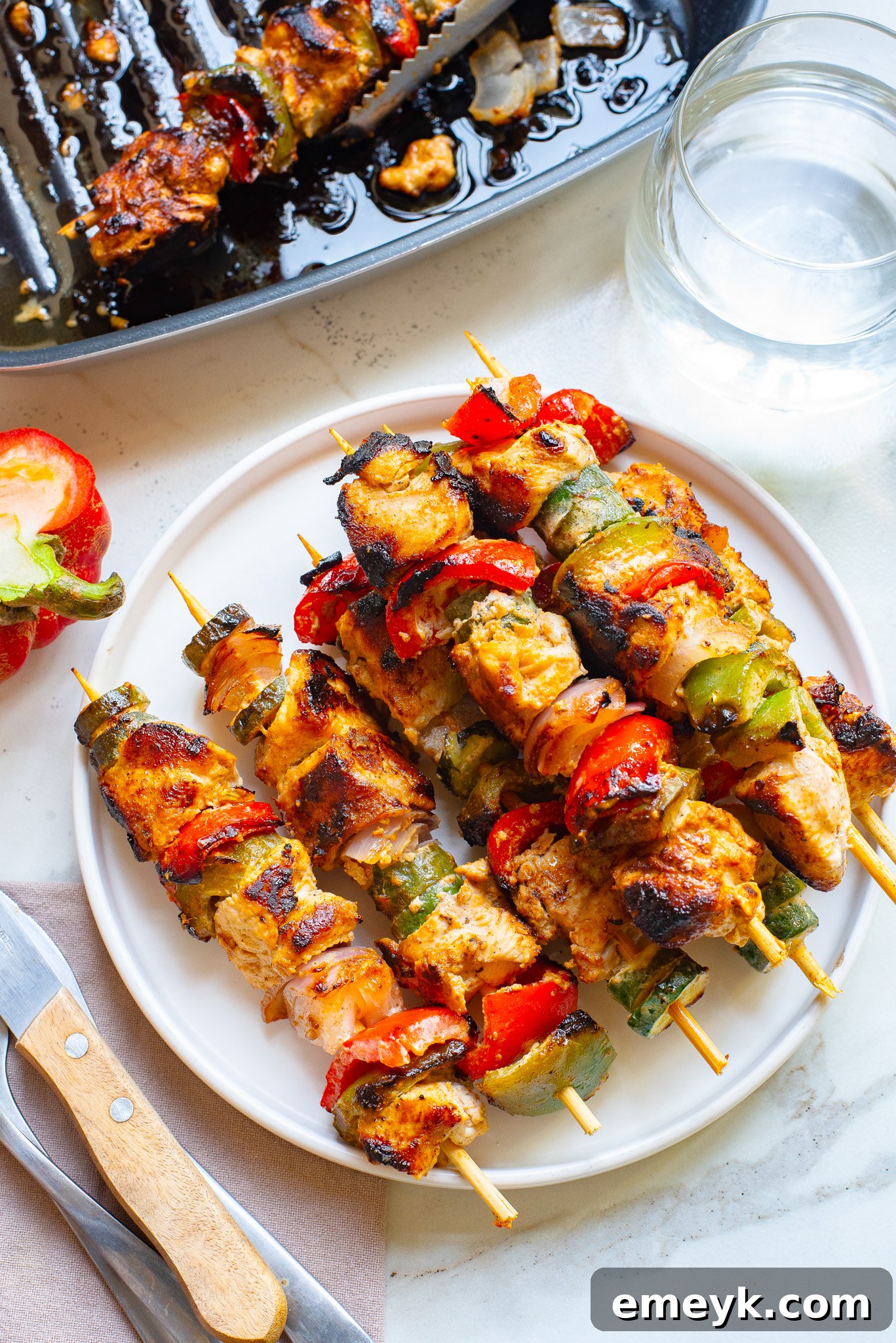 Lemon-Herb Mediterranean Chicken Skewers 7 Plated Greek Marinated Chicken Kabobs with Lemon, garnished with fresh herbs and a side of dipping sauce.