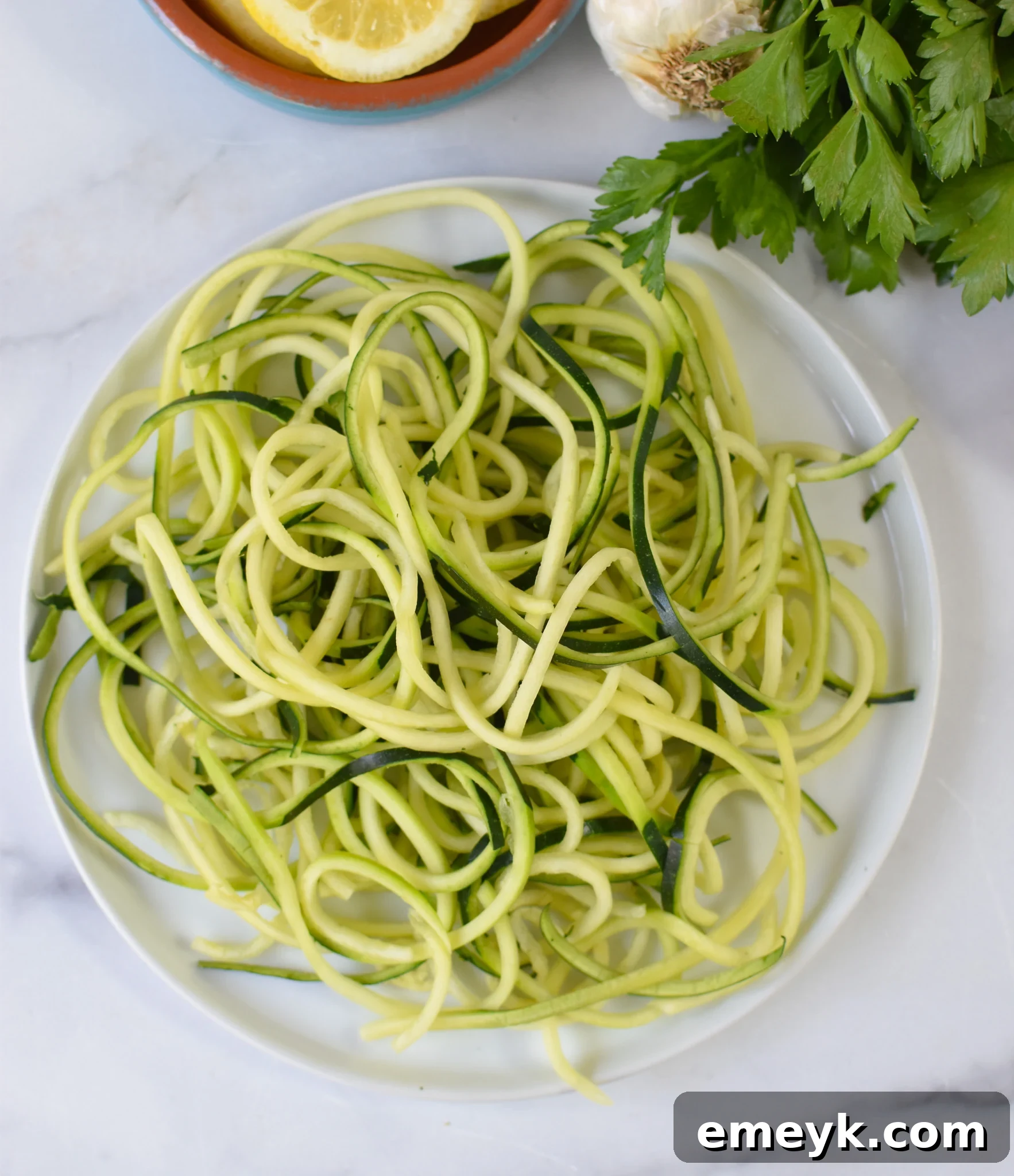 Creamy Zucchini Noodle Alfredo 5 Freshly spiralized zucchini noodles on a plate, ready for cooking in the Alfredo Zoodles Recipe.