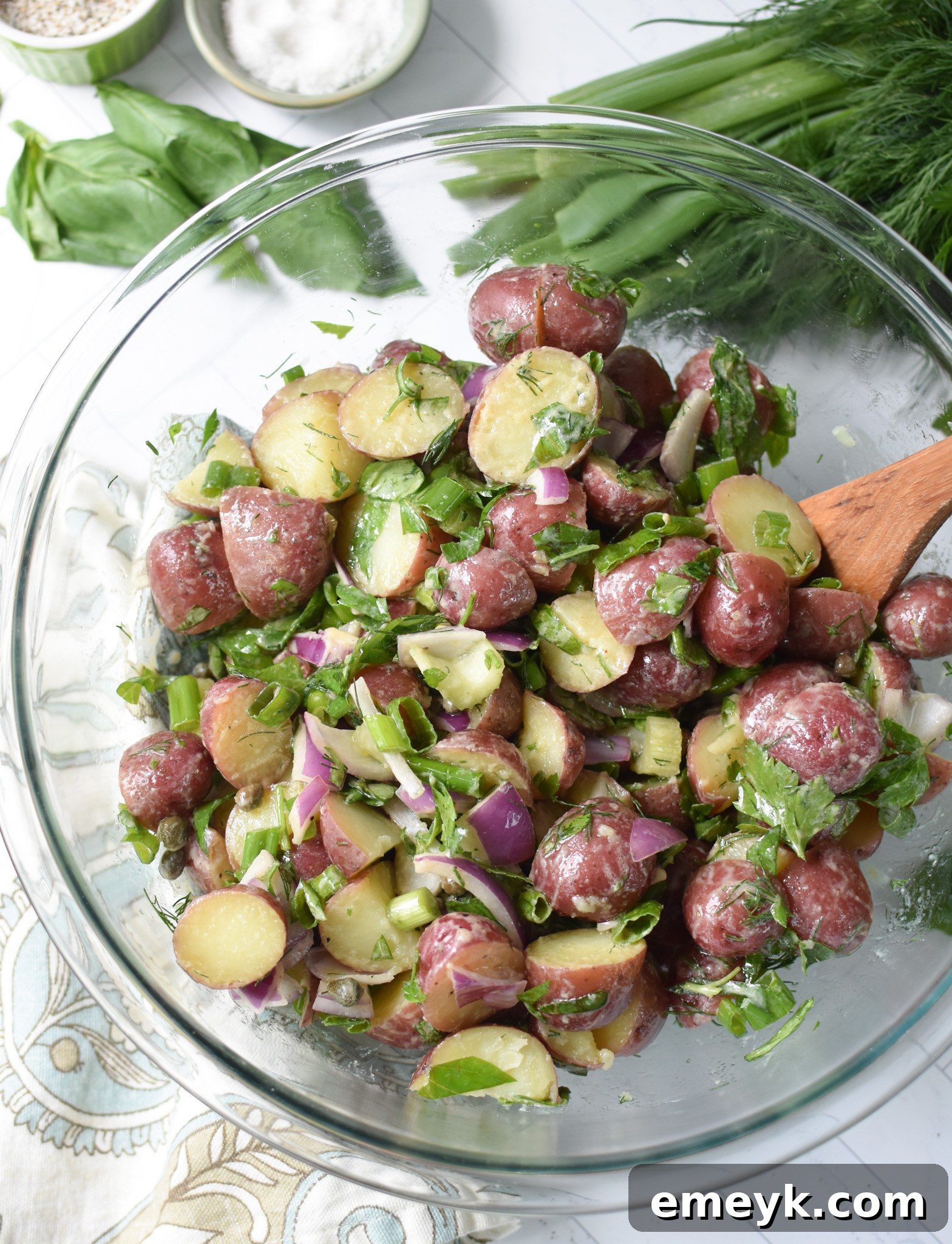Bright & Zesty Potato Salad 12 A large glass bowl filled with the colorful No Mayo Potato Salad, featuring tender potatoes, crisp vegetables, and fresh herbs, with a serving spoon nestled in it, ready for the final dressing.