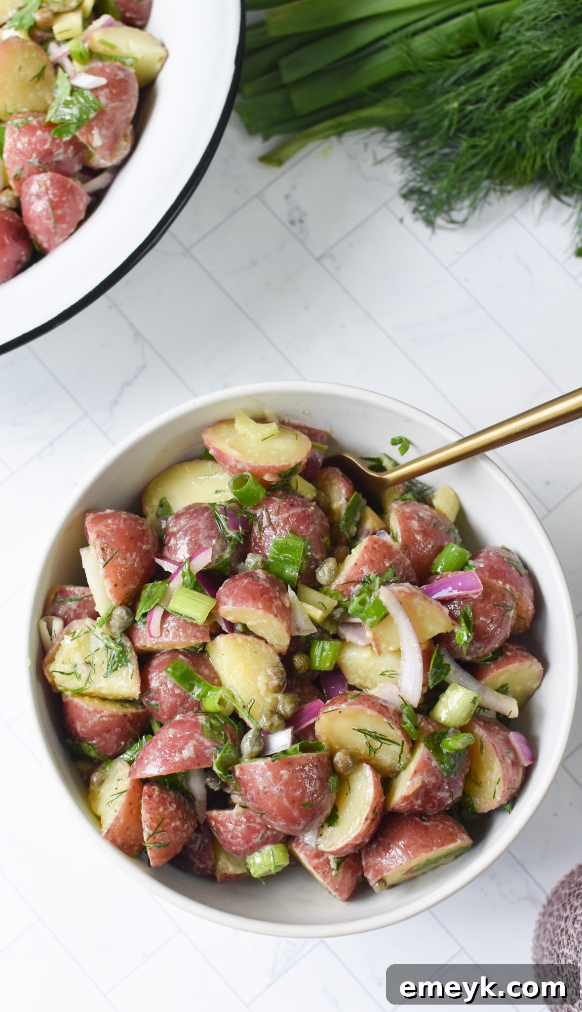 Bright & Zesty Potato Salad 7 A delicious serving of No Mayo Potato Salad in a white bowl, with a gold serving spoon dipped into it, ready to be enjoyed as a refreshing side.